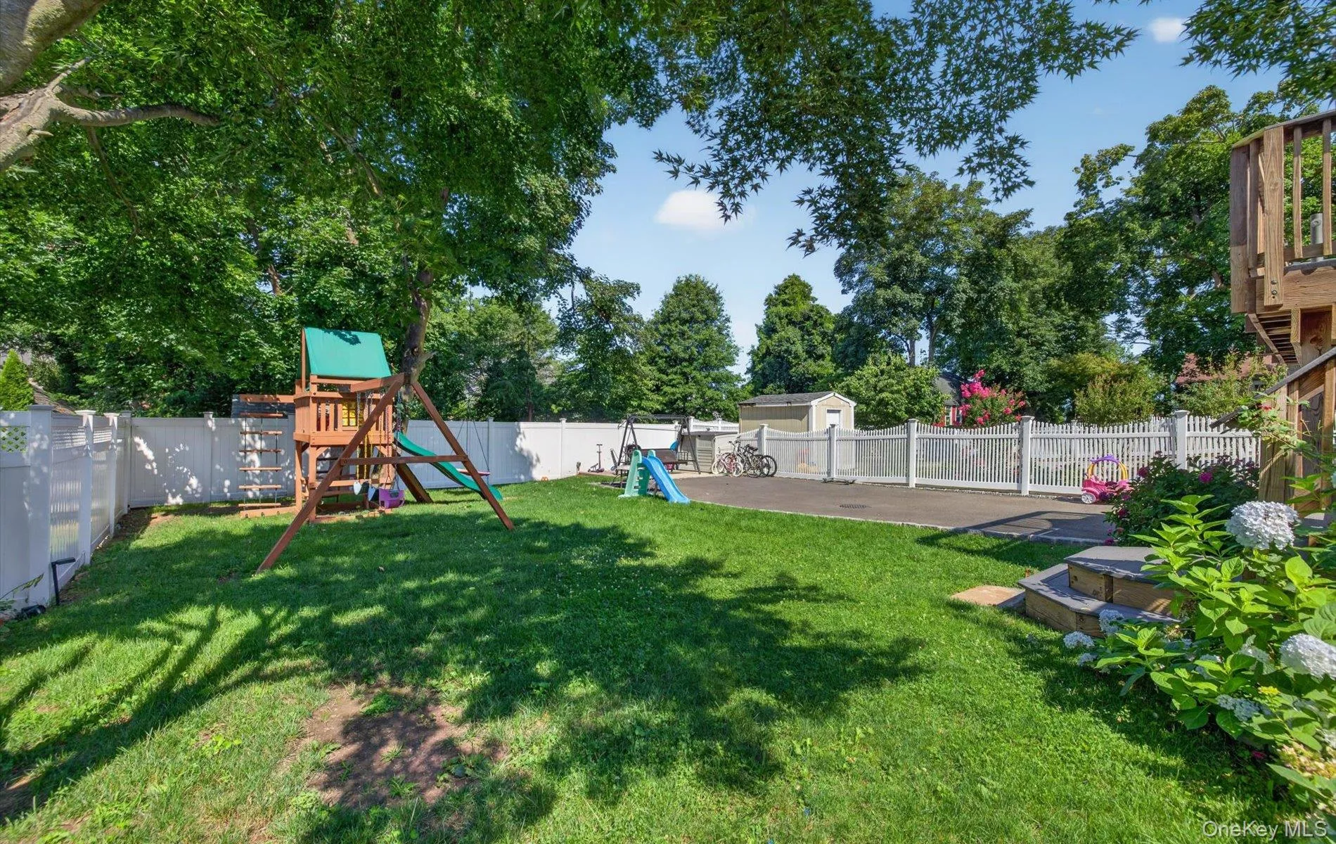 Expansive rear yard featuring a manicured lawn, established shade tree, and white fencing Expansive rear yard featuring a manicured lawn, established shade tree, and white fencing