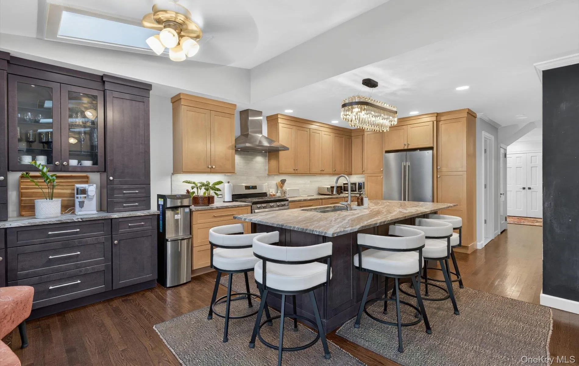 Spacious kitchen featuring a central island with countertop seating, stainless steel appliances, wood-finish flooring, a skylight, and a decorative chandelier, Coffee Bar Spacious kitchen featuring a central island with countertop seating, stainless steel appliances, wood-finish flooring, a skylight, and a decorative chandelier, Coffee Bar