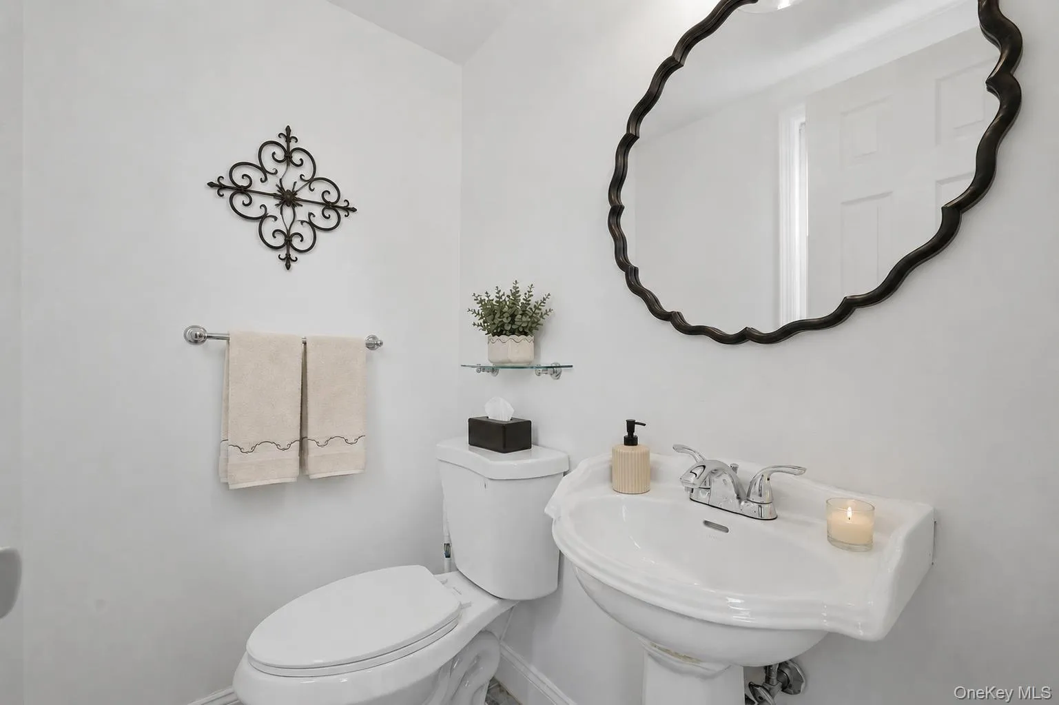 Half bath with pedestal sink with chrome faucet, complemented by a decorative black-framed mirror Half bath with pedestal sink with chrome faucet, complemented by a decorative black-framed mirror