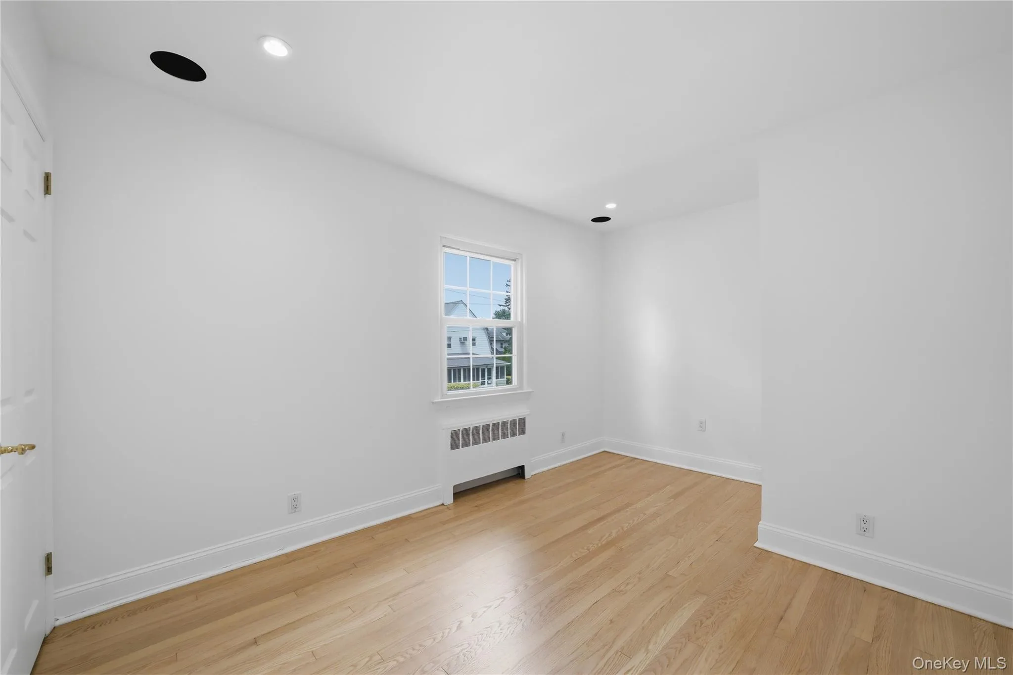 Bright 3rd bedroom featuring wood-finish flooring, white walls, and recessed lighting Bright 3rd bedroom featuring wood-finish flooring, white walls, and recessed lighting