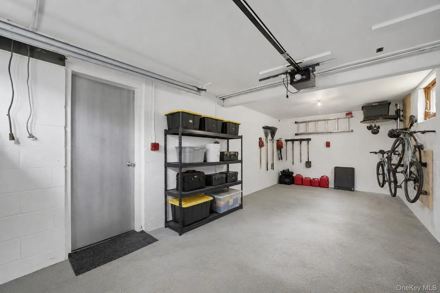 Spacious garage featuring a concrete floor, painted cinder block walls, and an overhead garage door opener mechanism Spacious garage featuring a concrete floor, painted cinder block walls, and an overhead garage door opener mechanism