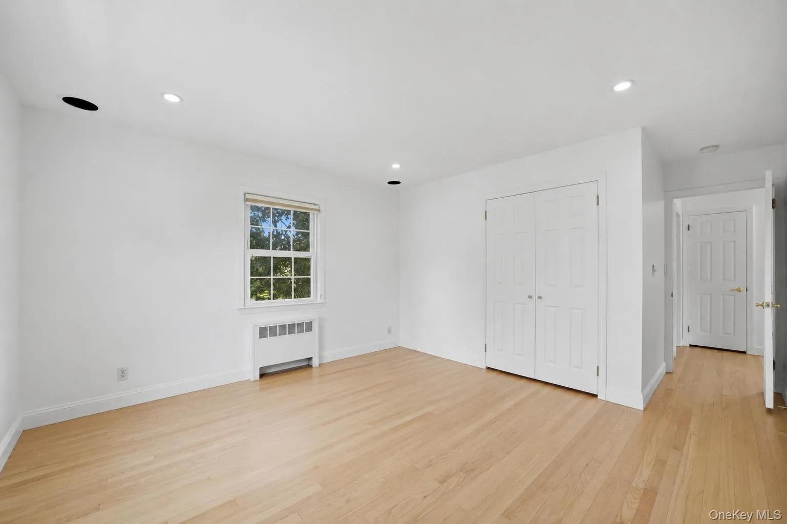 Bright 2nd bedroom featuring light wood-finish flooring, white walls, and a window with natural light Bright 2nd bedroom featuring light wood-finish flooring, white walls, and a window with natural light