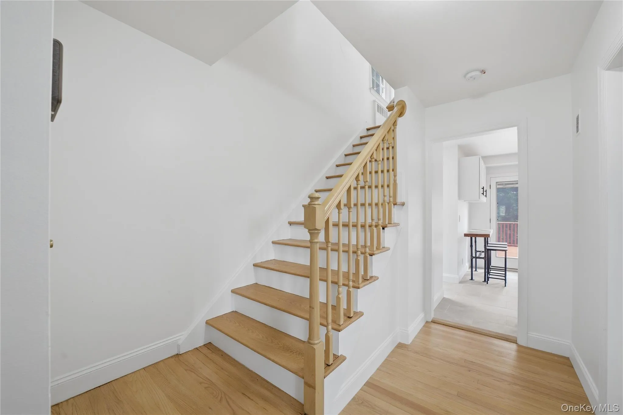 Hardwood flooring extends from the entryway throughout the lower level, complementing the natural wood staircase with white risers and railing Hardwood flooring extends from the entryway throughout the lower level, complementing the natural wood staircase with white risers and railing