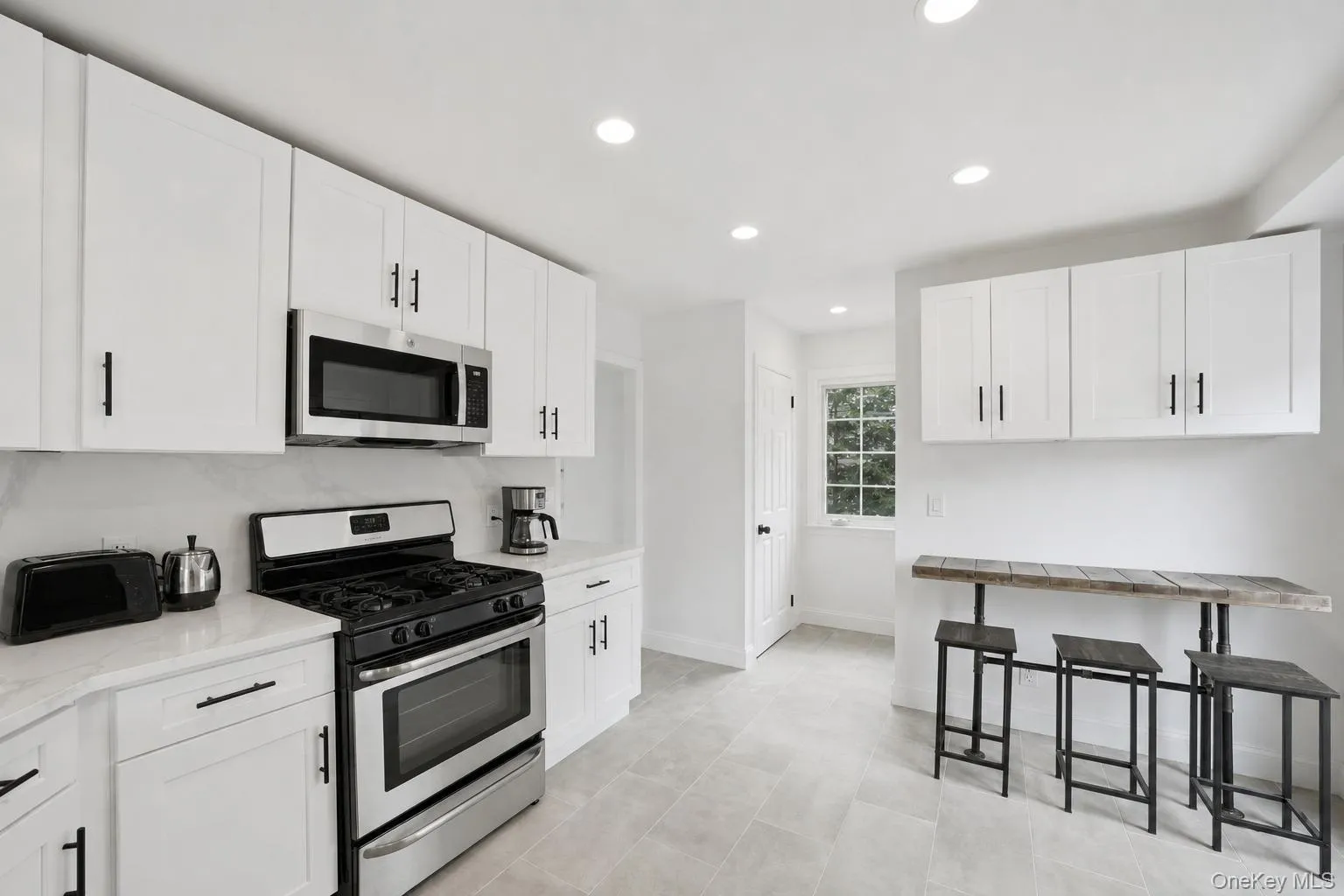 Kitchen featuring white shaker cabinetry, stainless steel appliances, a tile backsplash, and recessed lighting Kitchen featuring white shaker cabinetry, stainless steel appliances, a tile backsplash, and recessed lighting