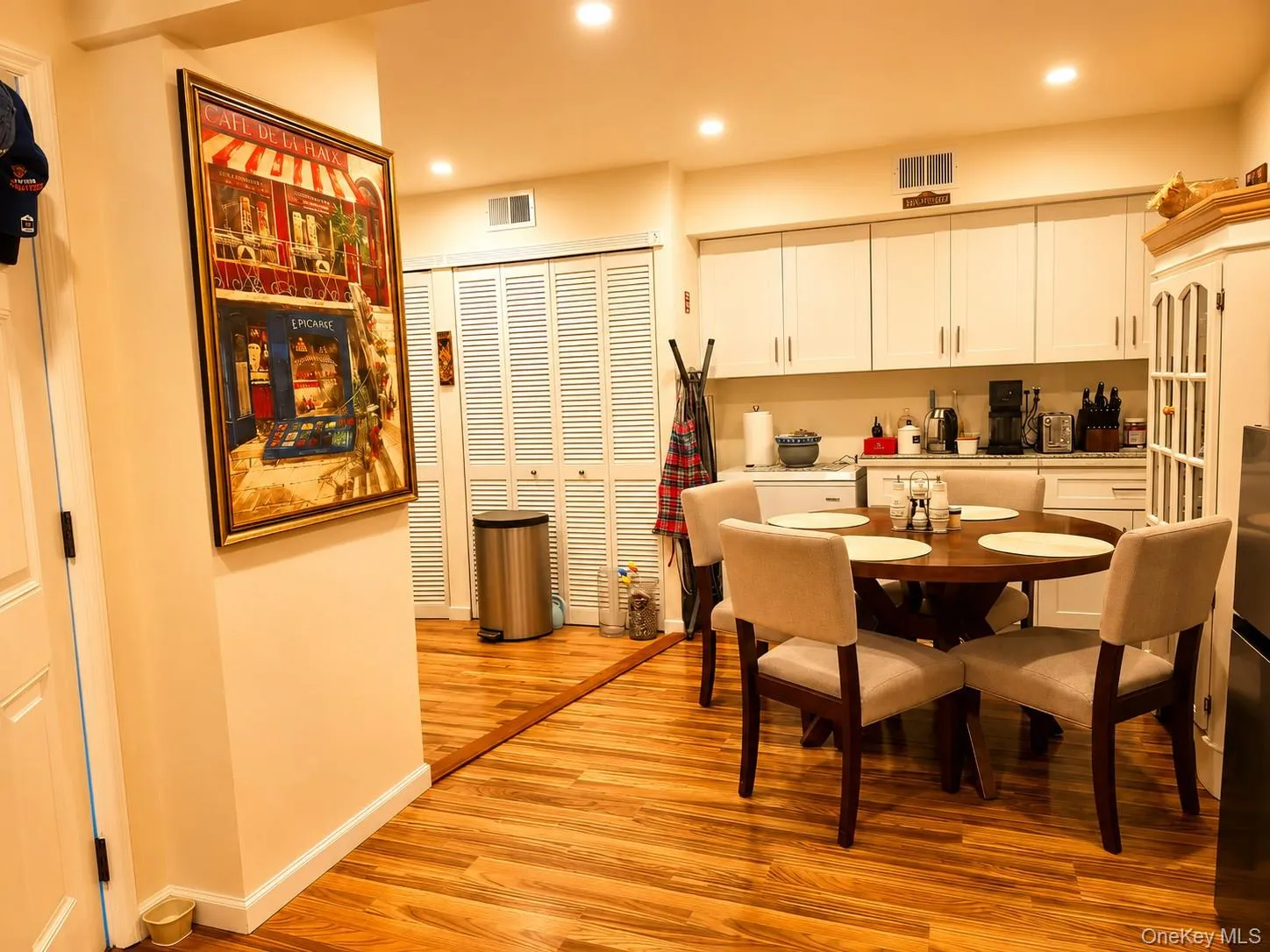 Kitchen area featuring wood-finish flooring, white cabinetry, recessed lighting, and louvered bifold doors Kitchen area featuring wood-finish flooring, white cabinetry, recessed lighting, and louvered bifold doors
