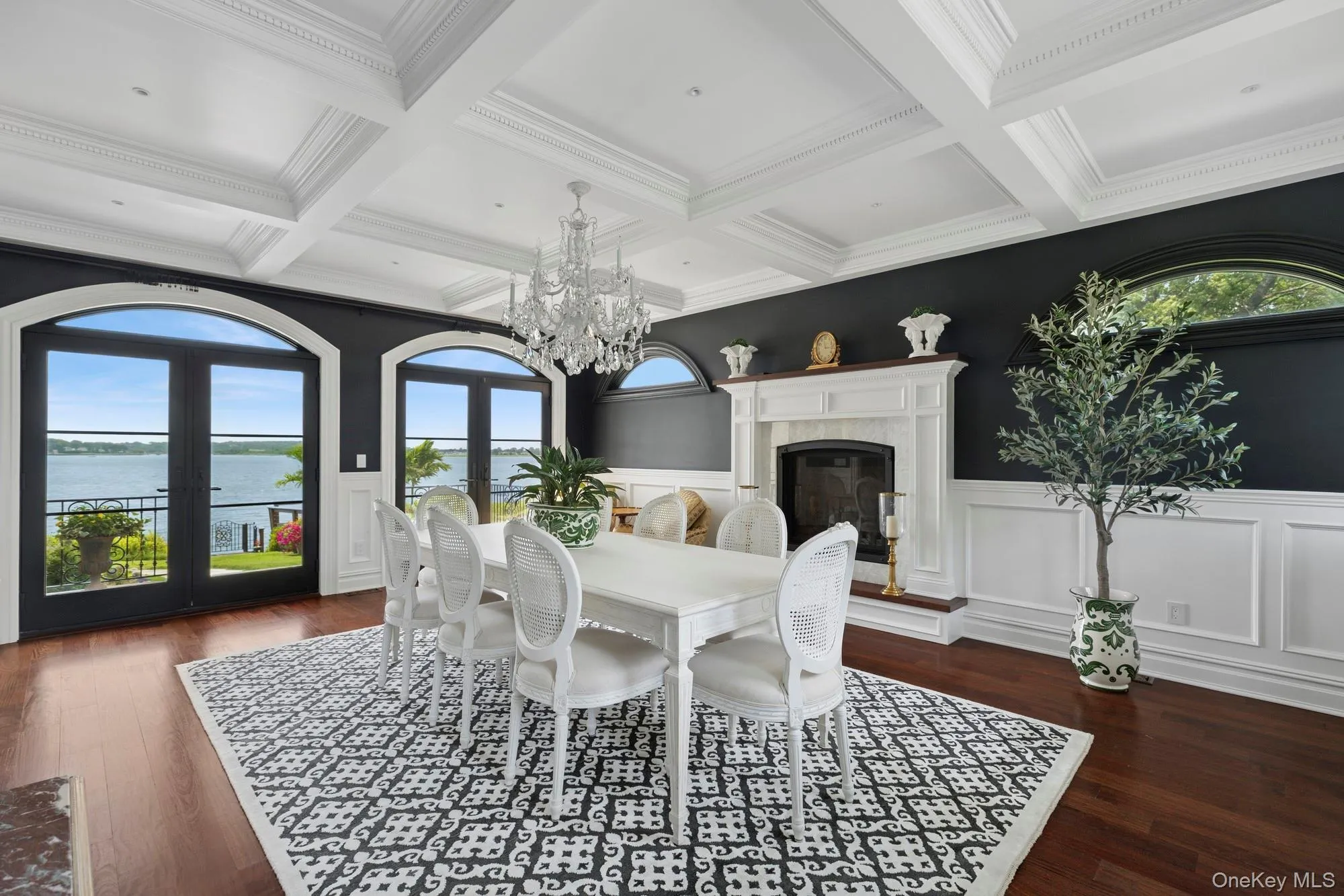 Dining room featuring french doors, a water view, beamed ceiling, dark wood-type flooring, and a chandelier Dining room featuring french doors, a water view, beamed ceiling, dark wood-type flooring, and a chandelier