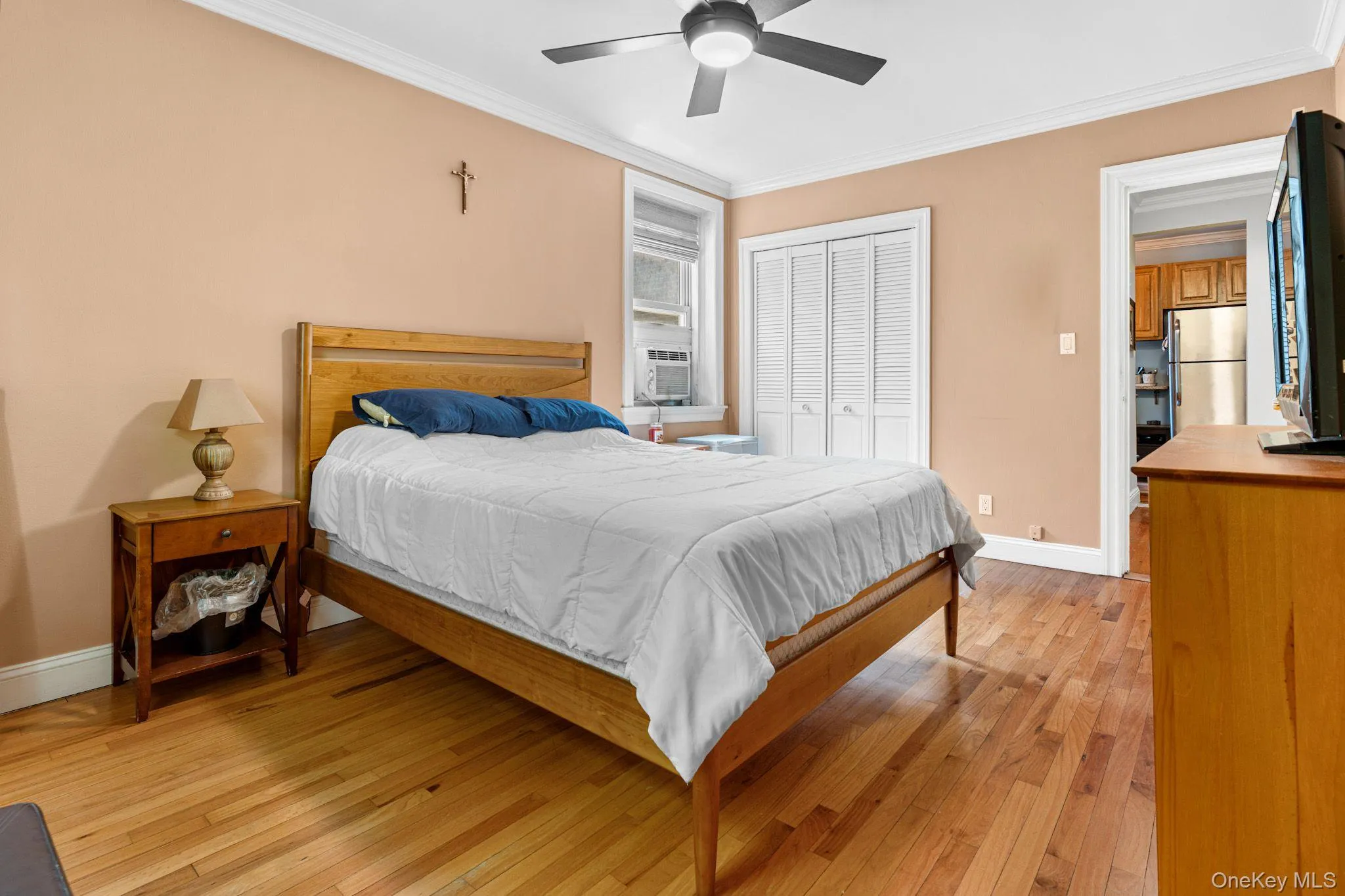 Bedroom featuring wood-finish flooring, crown molding, and two windows with natural light Bedroom featuring wood-finish flooring, crown molding, and two windows with natural light