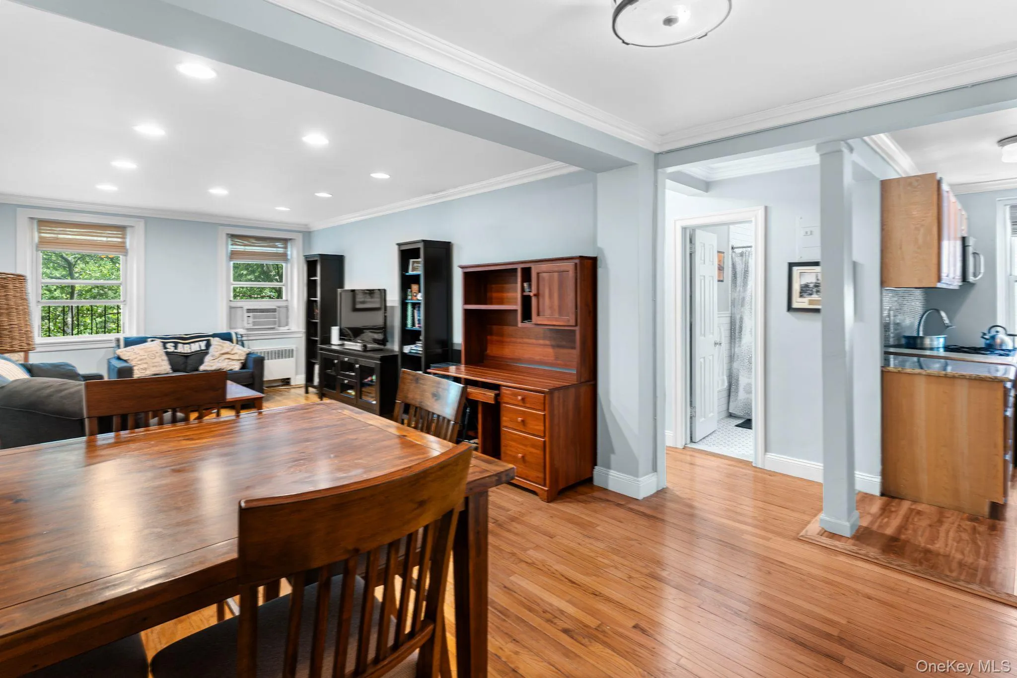 Open-concept living space featuring wood-finish flooring, recessed lighting, crown molding, and multiple windows Open-concept living space featuring wood-finish flooring, recessed lighting, crown molding, and multiple windows