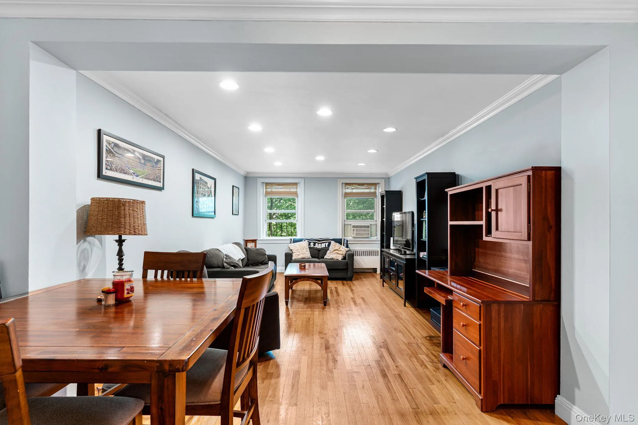 Open-concept living space featuring wood-finish flooring, recessed lighting, crown molding, and multiple windows Open-concept living space featuring wood-finish flooring, recessed lighting, crown molding, and multiple windows