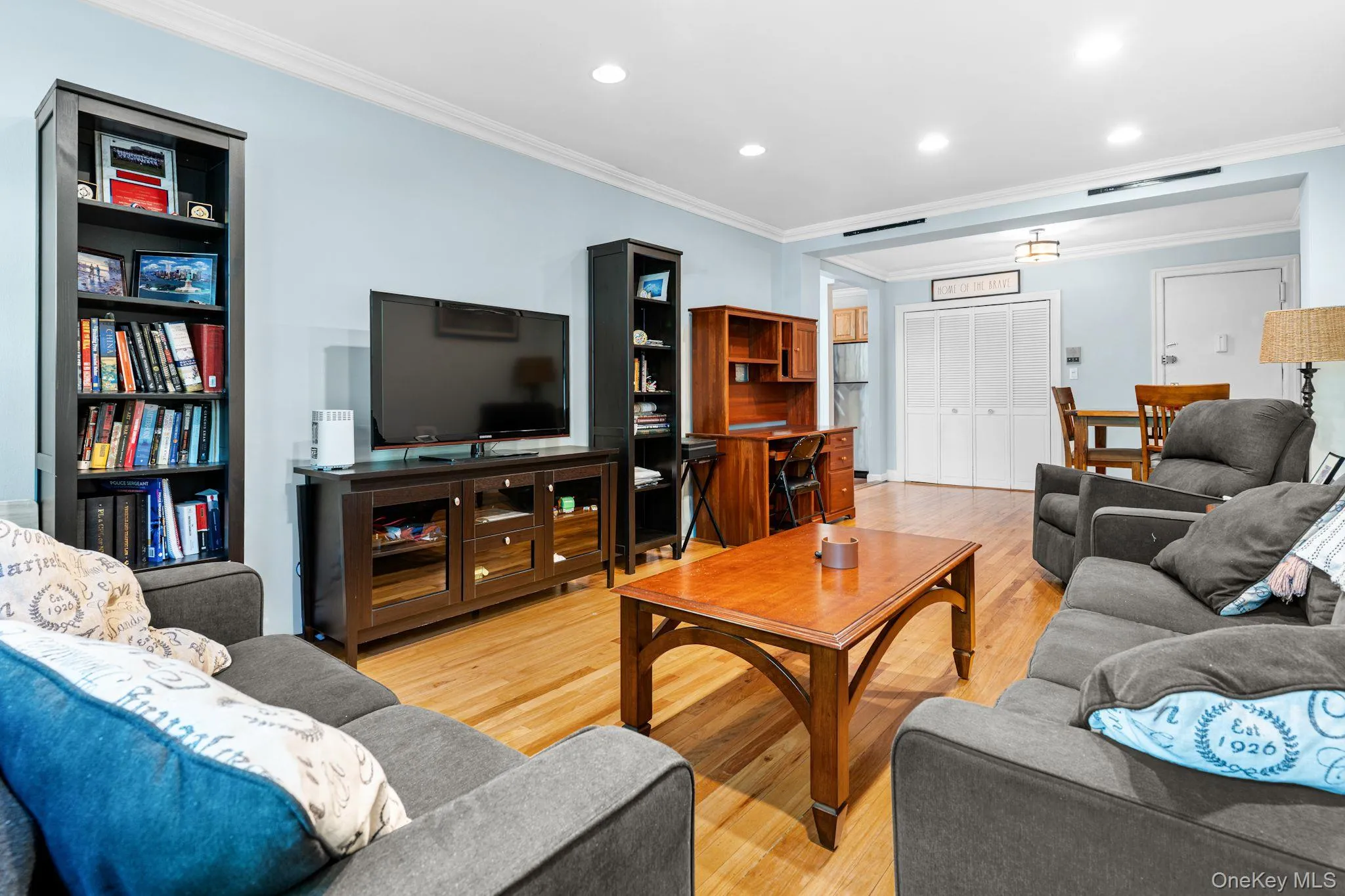 Open-concept living space featuring wood-finish flooring, recessed lighting, crown molding, and multiple windows Open-concept living space featuring wood-finish flooring, recessed lighting, crown molding, and multiple windows