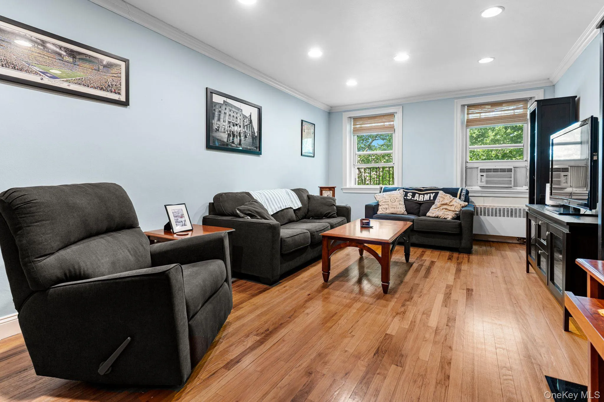 Open-concept living space featuring wood-finish flooring, recessed lighting, crown molding, and multiple windows Open-concept living space featuring wood-finish flooring, recessed lighting, crown molding, and multiple windows