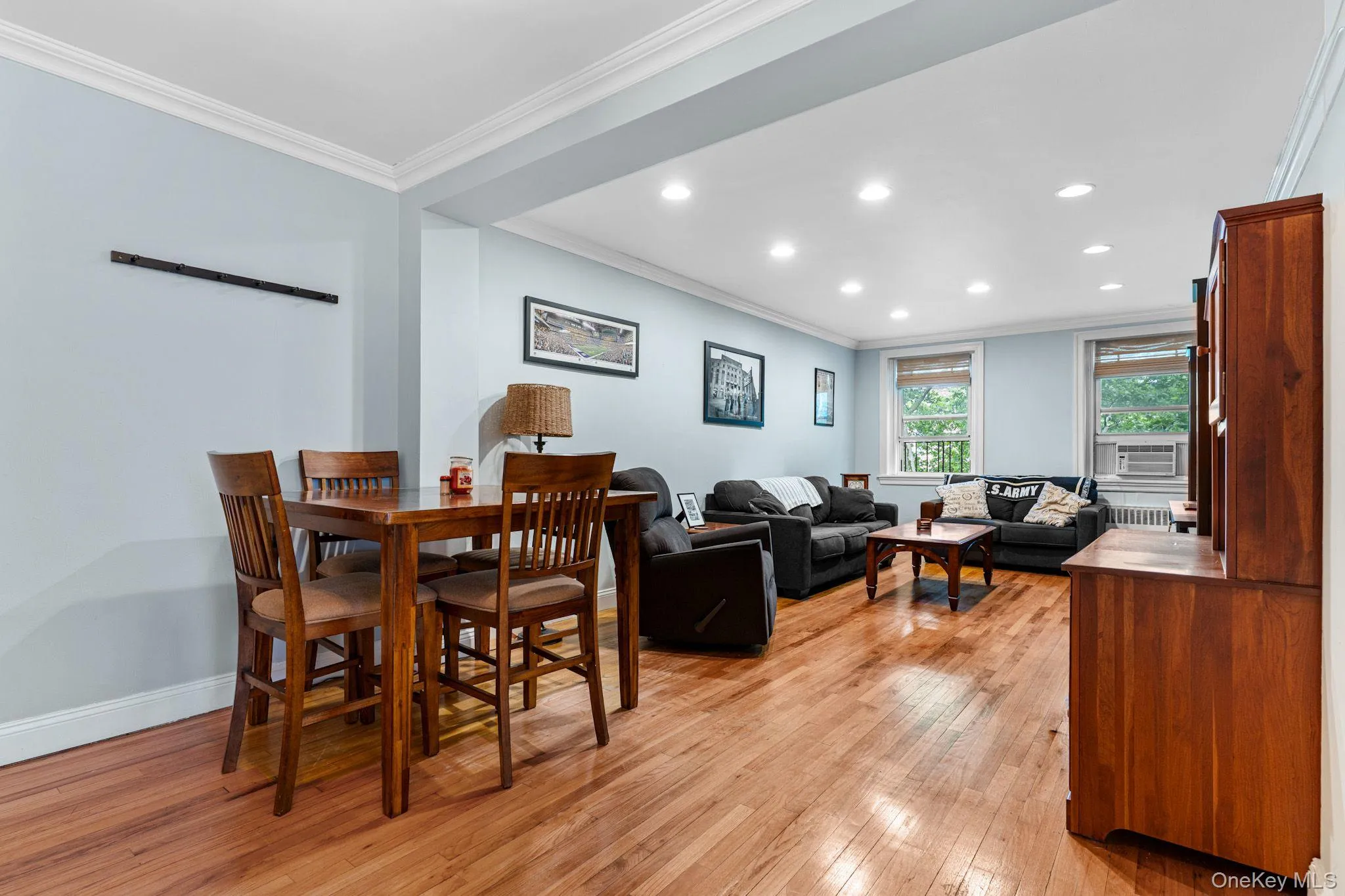 Open-concept living space featuring wood-finish flooring, recessed lighting, crown molding, and multiple windows Open-concept living space featuring wood-finish flooring, recessed lighting, crown molding, and multiple windows