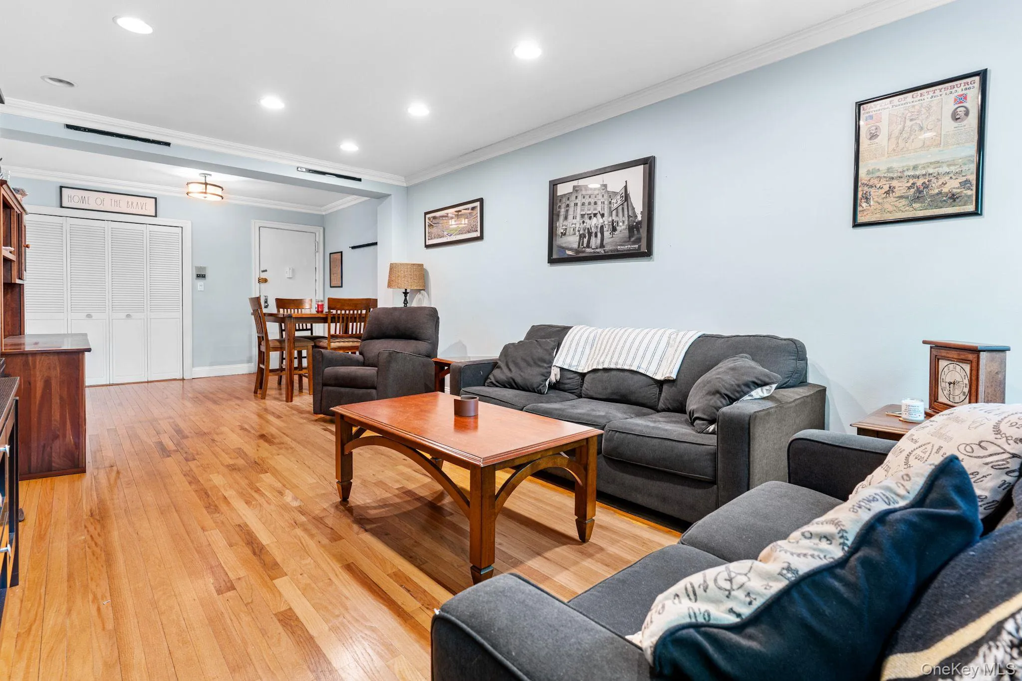 Open-concept living space featuring wood-finish flooring, recessed lighting, crown molding, and multiple windows Open-concept living space featuring wood-finish flooring, recessed lighting, crown molding, and multiple windows