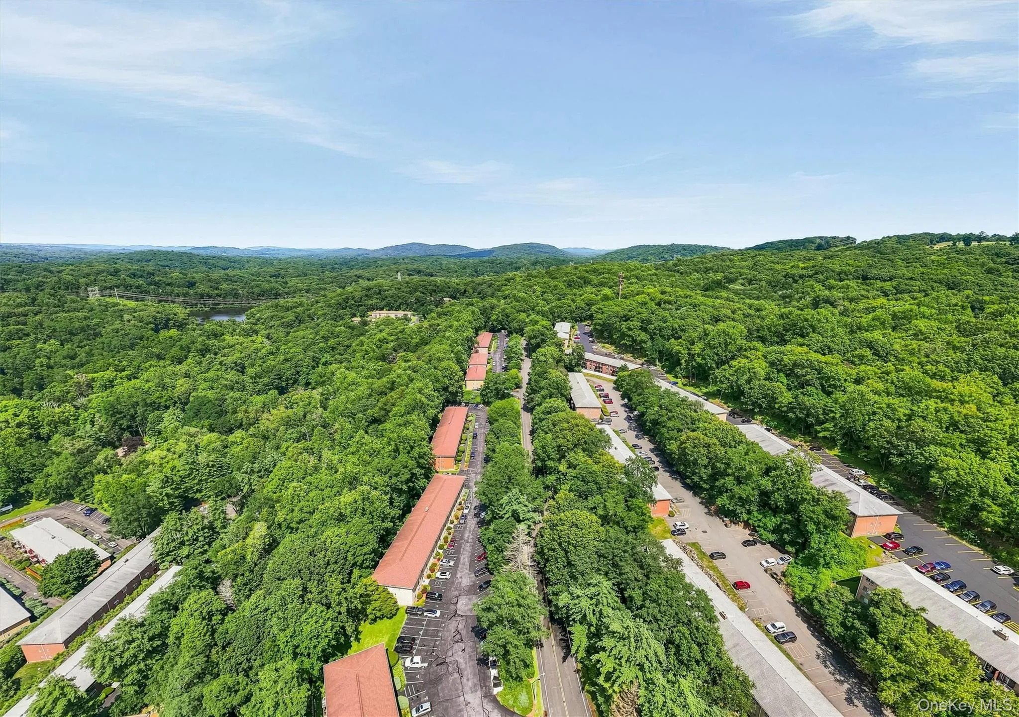 Aerial view showcasing expansive tree-lined property with multiple residential structures featuring red tile roofing, paved driveways, and mature landscaping throughout Aerial view showcasing expansive tree-lined property with multiple residential structures featuring red tile roofing, paved driveways, and mature landscaping throughout
