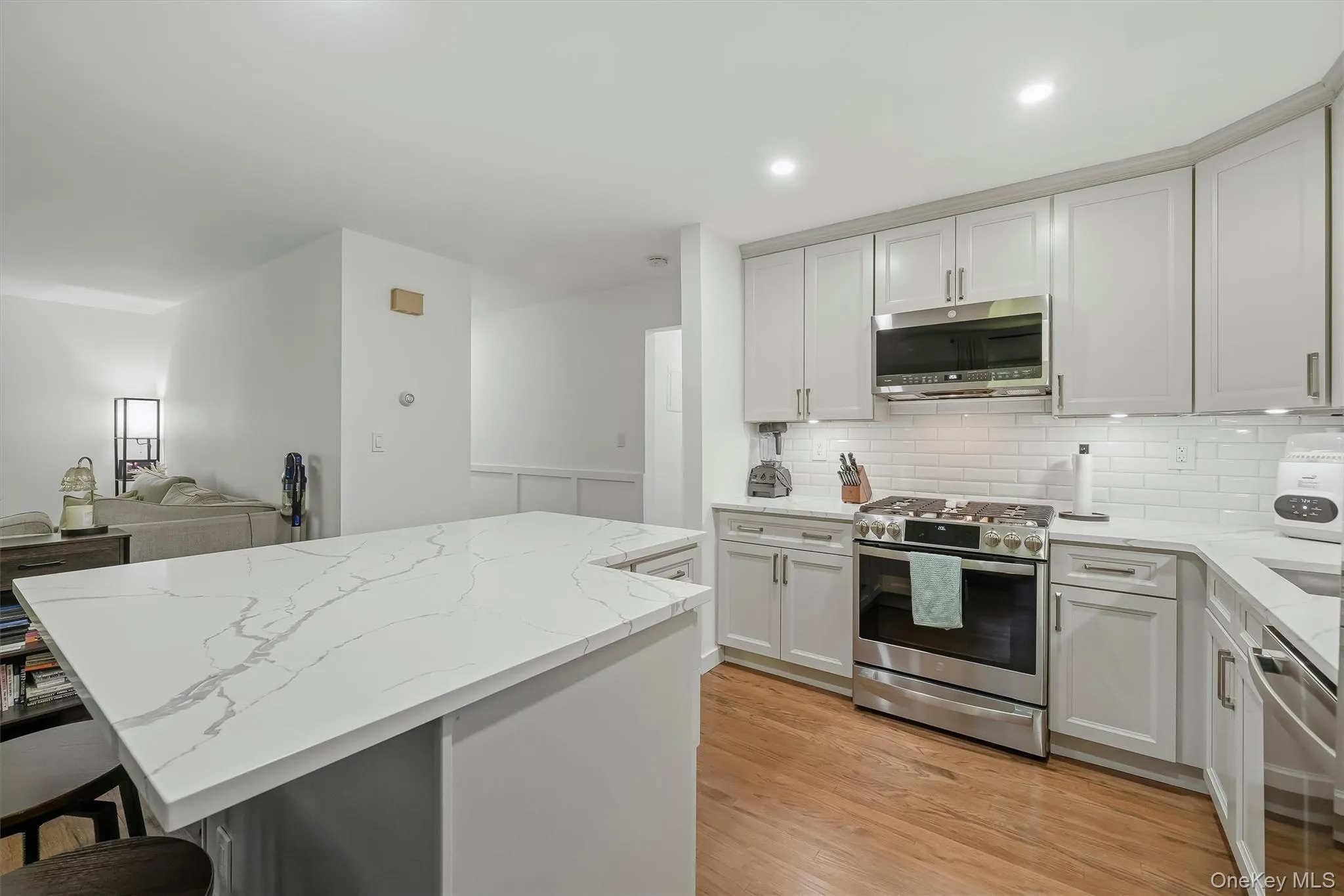 Modern kitchen featuring white cabinetry with stainless steel hardware, white subway tile backsplash, and stainless steel appliances including a built-in microwave and gas range Modern kitchen featuring white cabinetry with stainless steel hardware, white subway tile backsplash, and stainless steel appliances including a built-in microwave and gas range
