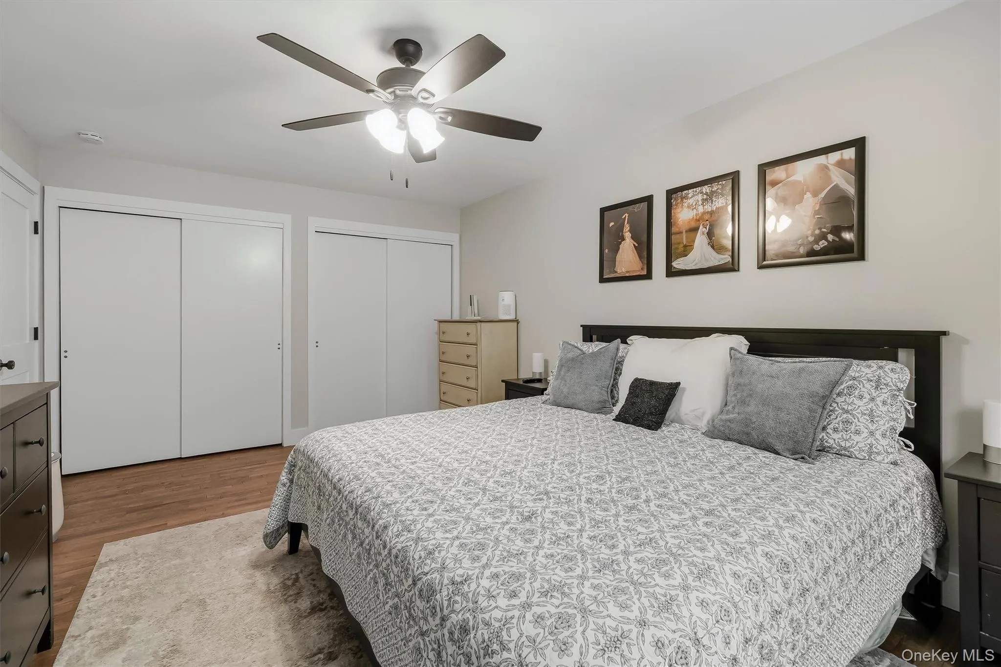Spacious room featuring wood-finish flooring, light gray wall paint, and a ceiling fan with integrated lighting Spacious room featuring wood-finish flooring, light gray wall paint, and a ceiling fan with integrated lighting