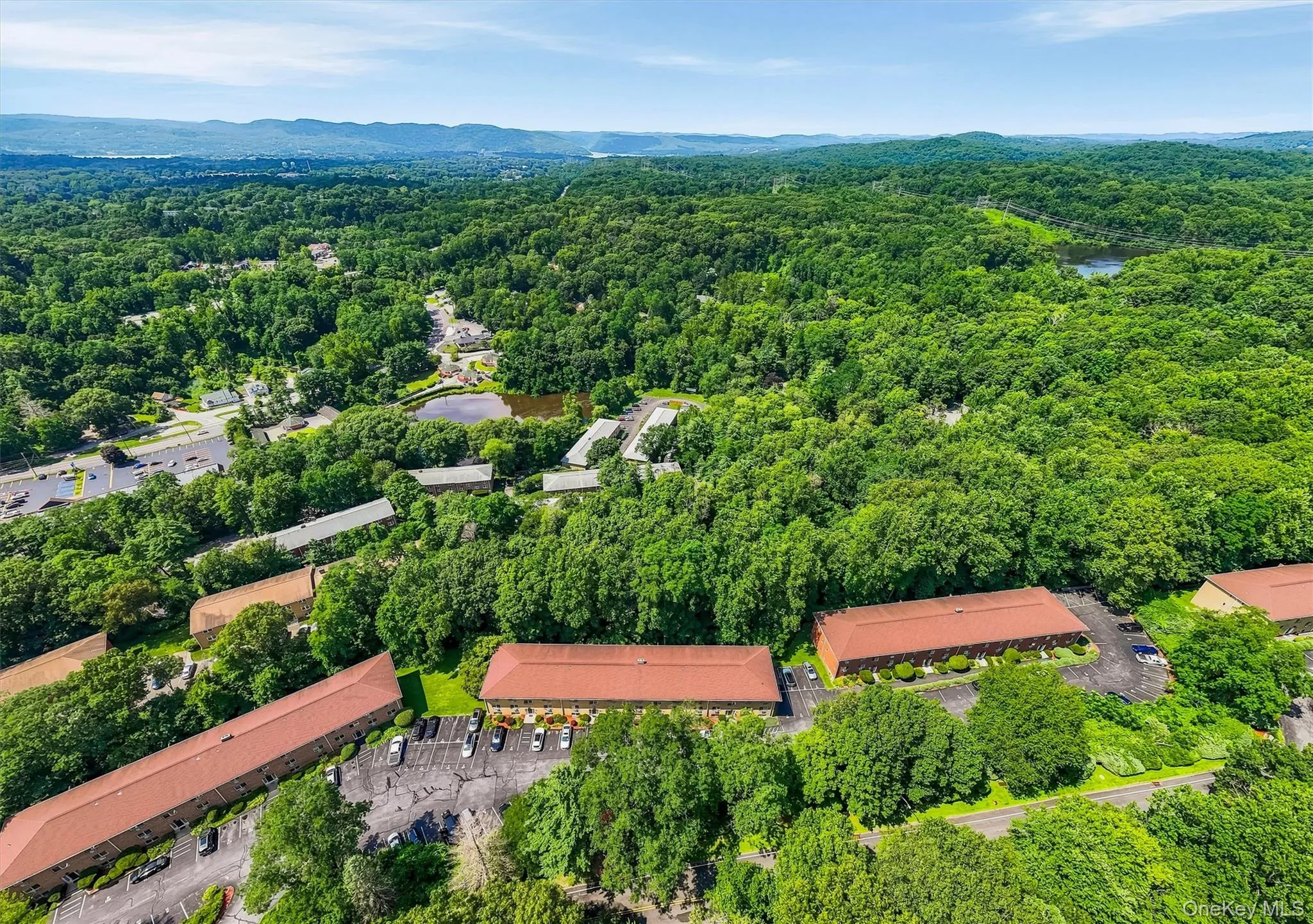 Expansive aerial view showcasing the property's substantial footprint with distinctive red-tile roofing, surrounded by mature tree canopy and lush landscaping Expansive aerial view showcasing the property's substantial footprint with distinctive red-tile roofing, surrounded by mature tree canopy and lush landscaping