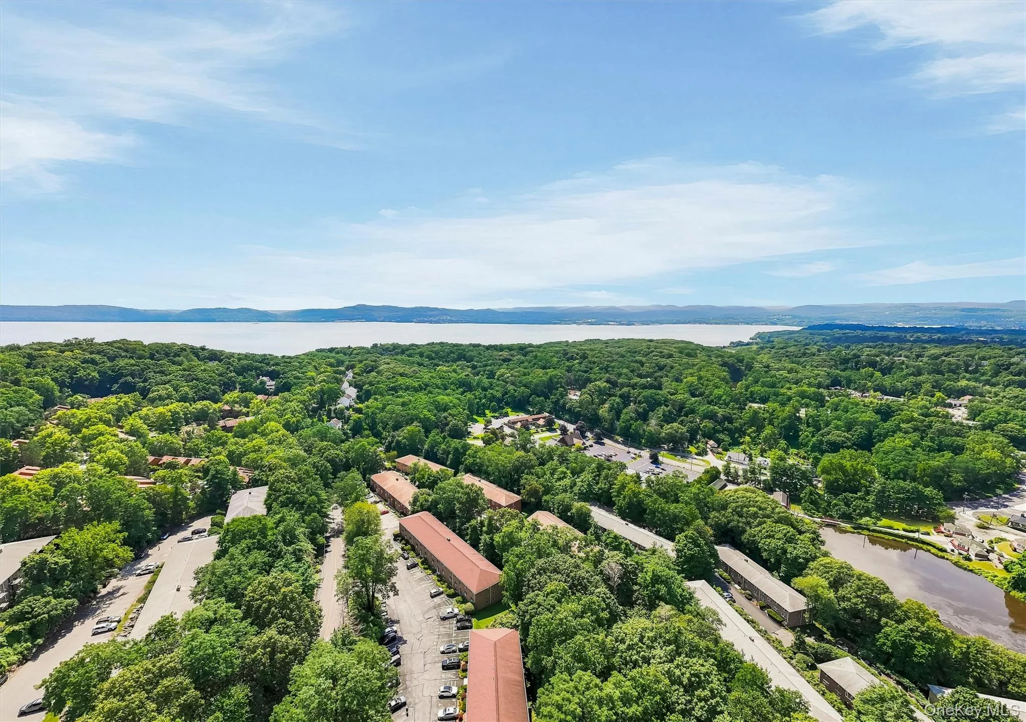 Aerial perspective showcasing mature tree canopy and verdant landscaping across expansive grounds, with waterfront visible in the distance and multiple residential structures distributed throughout the property Aerial perspective showcasing mature tree canopy and verdant landscaping across expansive grounds, with waterfront visible in the distance and multiple residential structures distributed throughout the property