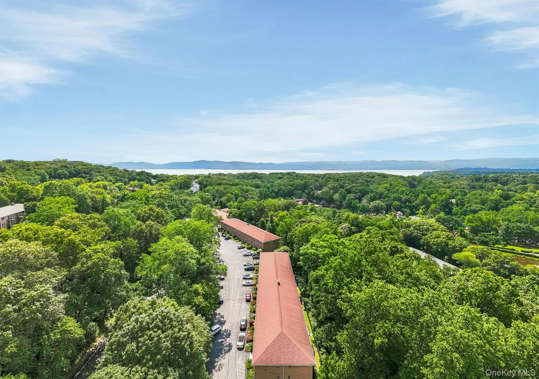 Aerial perspective showcasing the surrounding verdant landscape and distant body of water Aerial perspective showcasing the surrounding verdant landscape and distant body of water