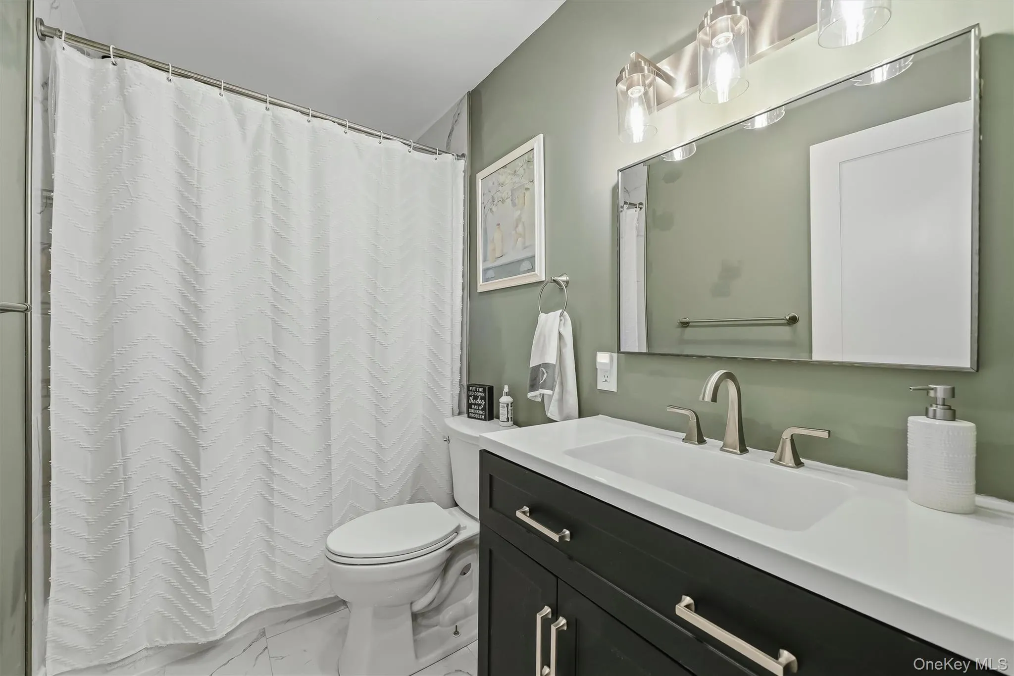 Spa-inspired primary bathroom featuring a dual-sink vanity with black cabinetry, white quartz countertop, and polished chrome hardware Spa-inspired primary bathroom featuring a dual-sink vanity with black cabinetry, white quartz countertop, and polished chrome hardware