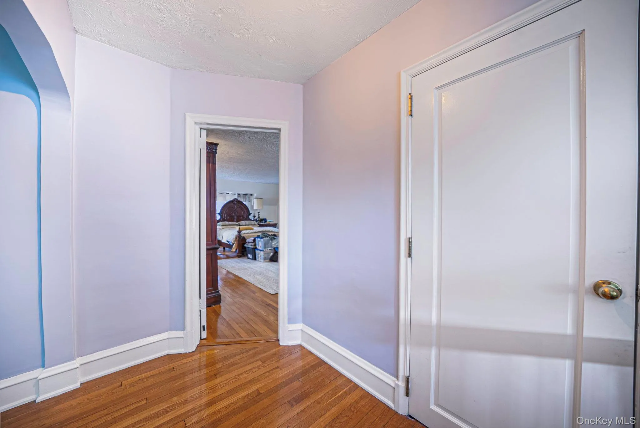 Hardwood flooring with a diagonal pattern, white trim work, and a white interior door with brass hardware Hardwood flooring with a diagonal pattern, white trim work, and a white interior door with brass hardware