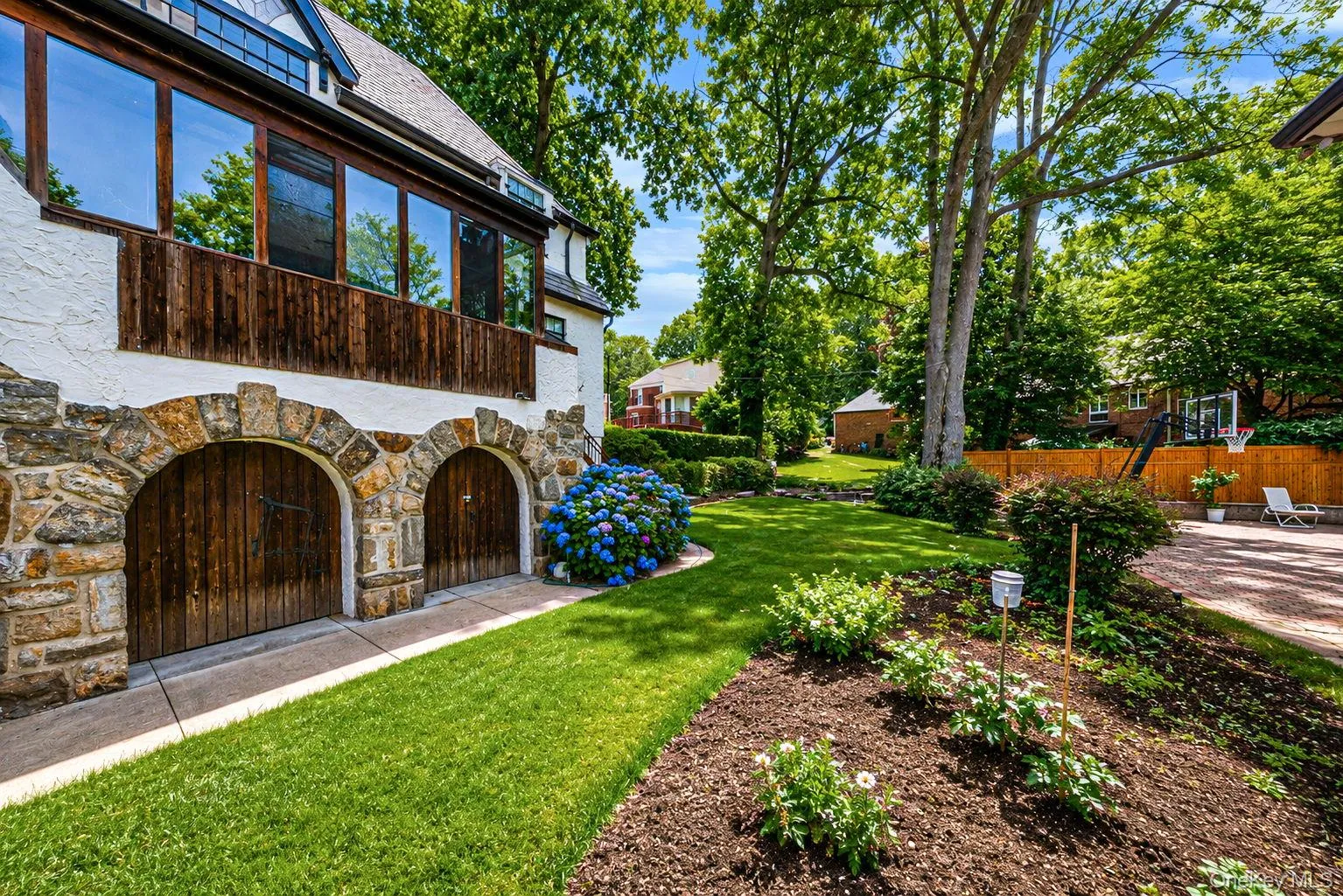 Stone-clad arched garage doors with wood paneling Stone-clad arched garage doors with wood paneling