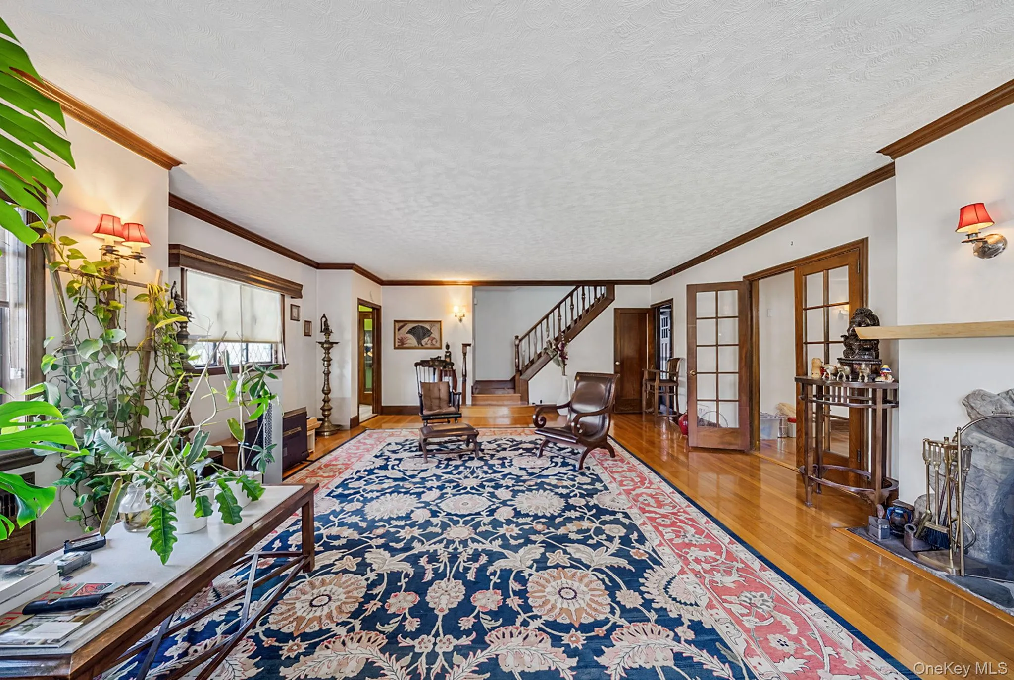 Spacious interior featuring hardwood flooring, detailed crown molding, a built-in fireplace, and double French doors with transom windows Spacious interior featuring hardwood flooring, detailed crown molding, a built-in fireplace, and double French doors with transom windows