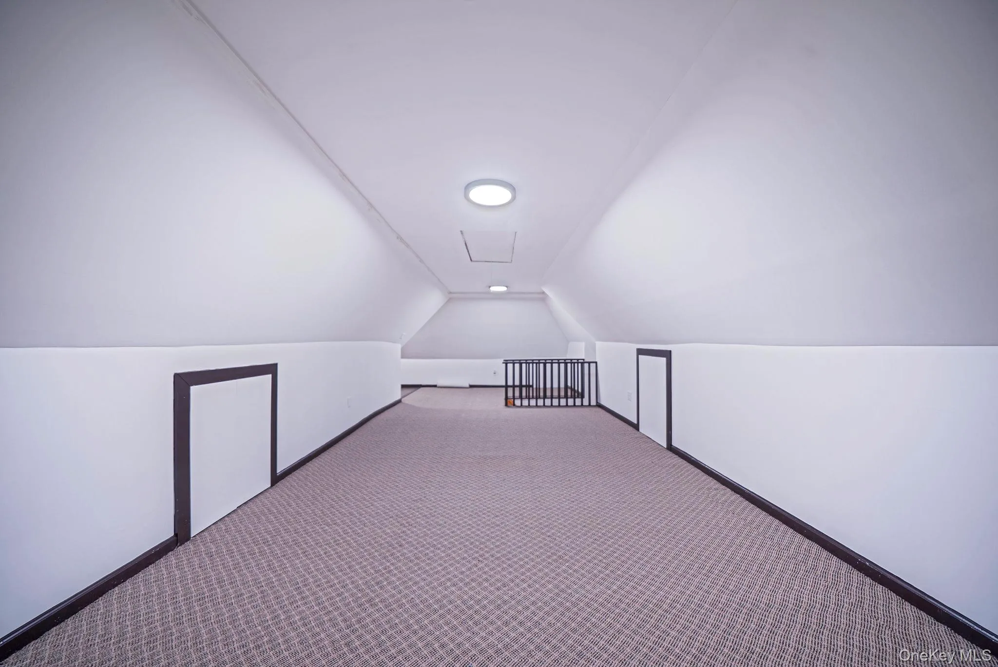 Expansive attic space featuring sloped ceilings, recessed lighting, patterned carpeting, and multiple integrated storage access points Expansive attic space featuring sloped ceilings, recessed lighting, patterned carpeting, and multiple integrated storage access points