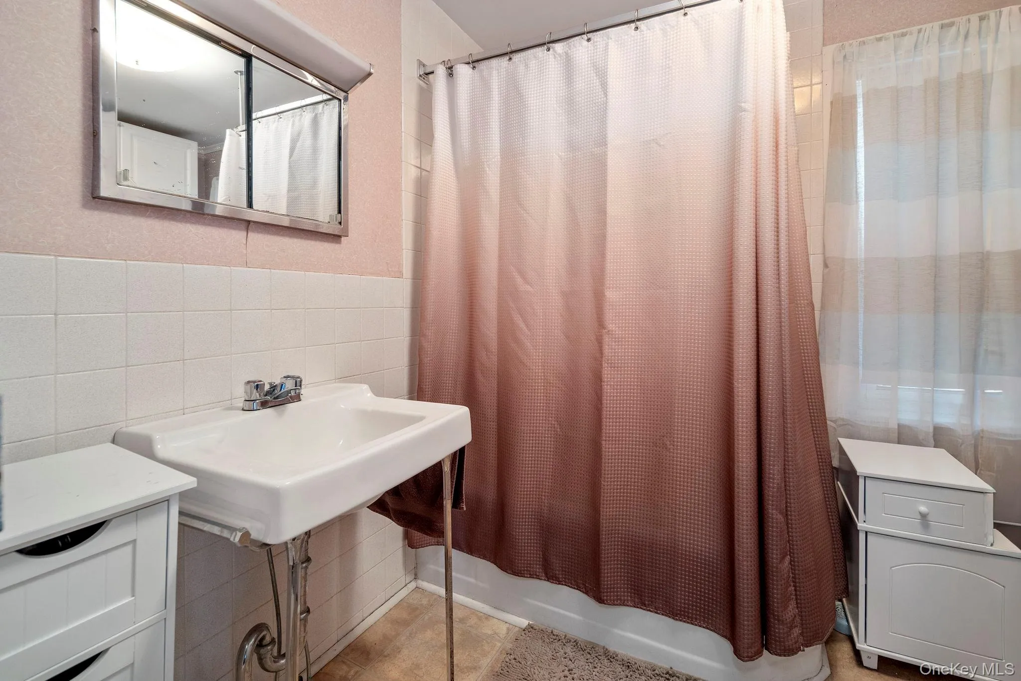 Bathroom featuring a wall-mounted sink with chrome faucet, white square tile wainscoting, and a mirrored medicine cabinet Bathroom featuring a wall-mounted sink with chrome faucet, white square tile wainscoting, and a mirrored medicine cabinet