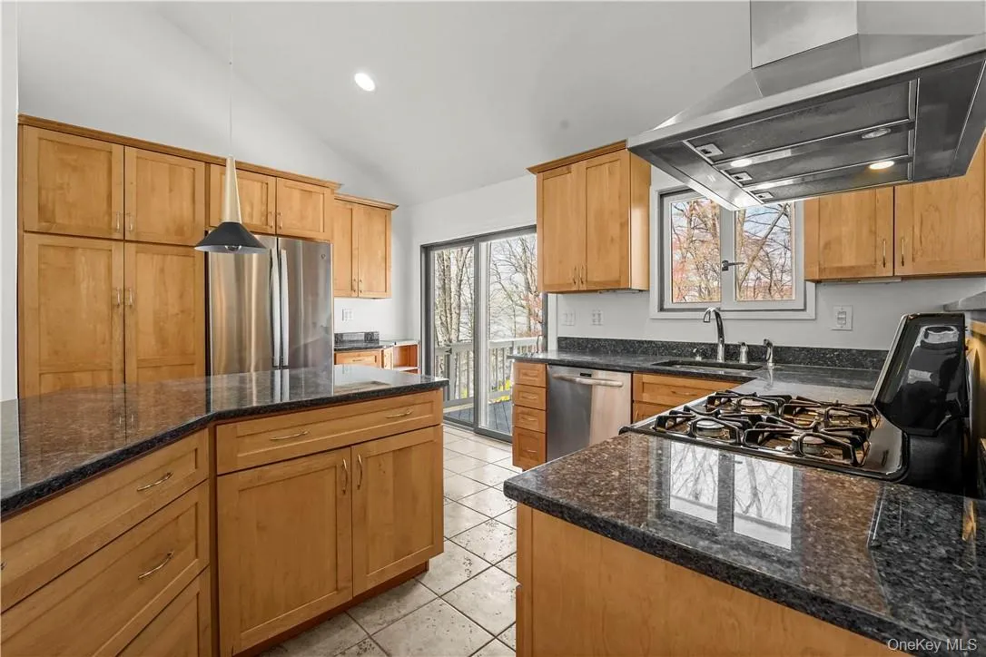 Kitchen with stainless appliances, gas stove, granite counters and sliding glass door to deck. Kitchen with stainless appliances, gas stove, granite counters and sliding glass door to deck.