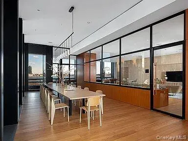 Spacious interior with wood-finish flooring, a contemporary linear chandelier, and floor-to-ceiling windows Spacious interior with wood-finish flooring, a contemporary linear chandelier, and floor-to-ceiling windows
