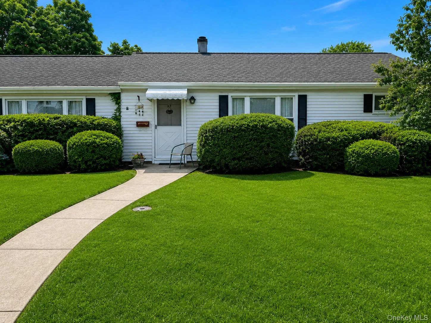 Single-story residence featuring white siding, a dark shingle roof, and black window shutters Single-story residence featuring white siding, a dark shingle roof, and black window shutters