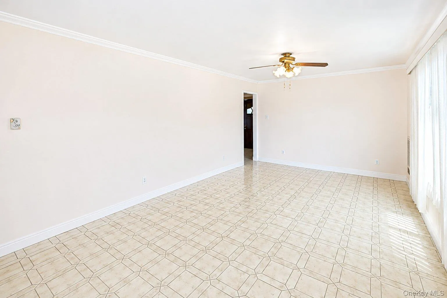 Spacious room featuring geometric tile flooring, crown molding, baseboards, and a ceiling fan with integrated lighting Spacious room featuring geometric tile flooring, crown molding, baseboards, and a ceiling fan with integrated lighting