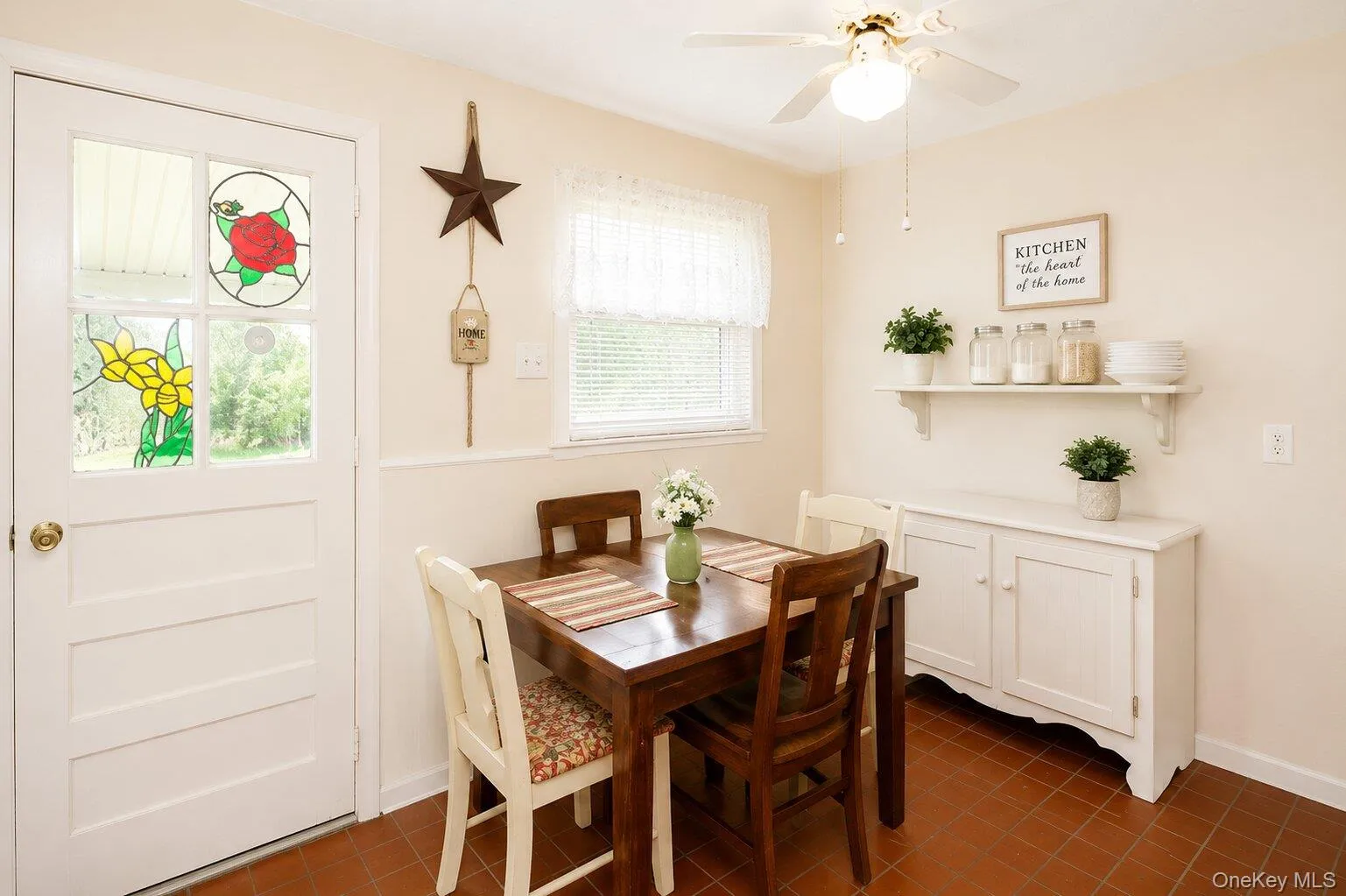 Dining area featuring terracotta-style tile flooring, a built-in white cabinet, and a wall-mounted shelving unit Dining area featuring terracotta-style tile flooring, a built-in white cabinet, and a wall-mounted shelving unit