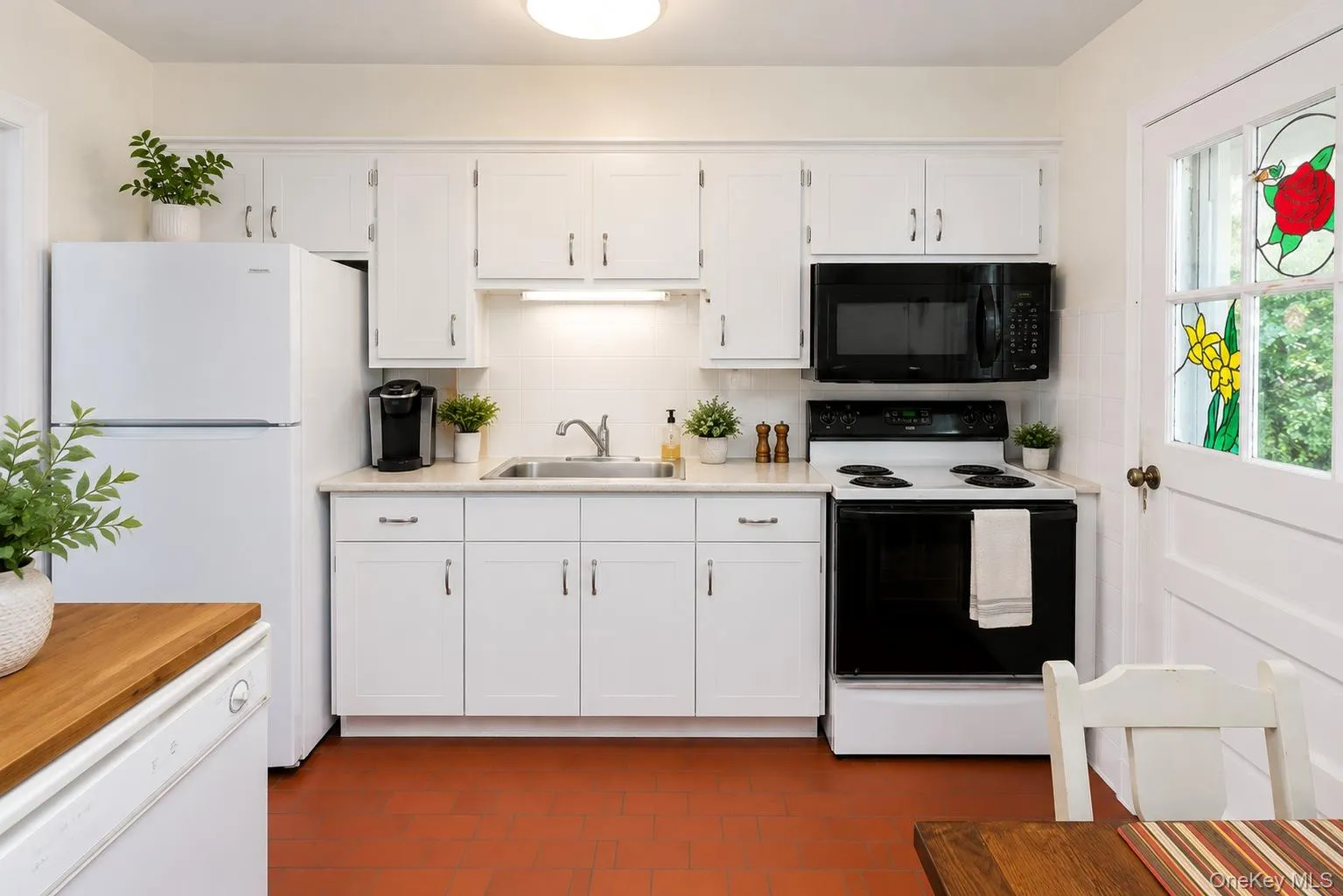 Kitchen featuring white cabinetry, a stainless steel sink, and light-toned countertops Kitchen featuring white cabinetry, a stainless steel sink, and light-toned countertops