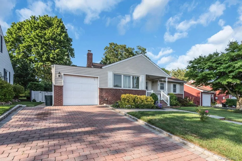 Ranch-style exterior featuring a brick and siding facade, an integrated single-car garage, a paver driveway, and a manicured lawn Ranch-style exterior featuring a brick and siding facade, an integrated single-car garage, a paver driveway, and a manicured lawn