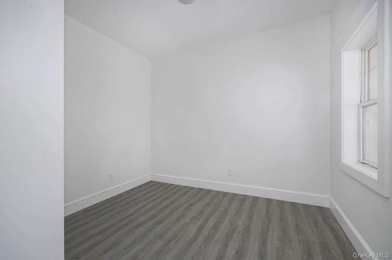 Unfurnished room with wood finished floors and vaulted ceiling Unfurnished room with wood finished floors and vaulted ceiling