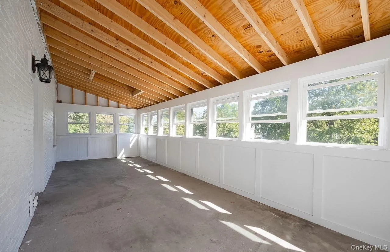 Unfurnished sunroom with vaulted ceiling, concrete flooring, and a decorative wall Unfurnished sunroom with vaulted ceiling, concrete flooring, and a decorative wall