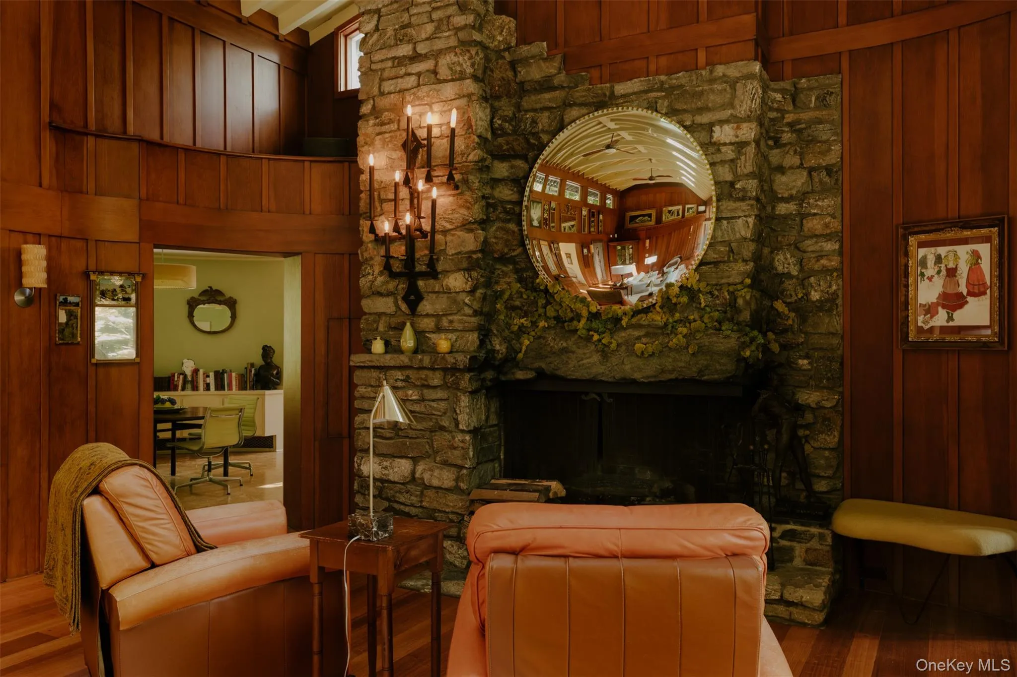 Stone fireplace with a large integrated hearth, featuring a black candelabra sconce and a round mirror Stone fireplace with a large integrated hearth, featuring a black candelabra sconce and a round mirror