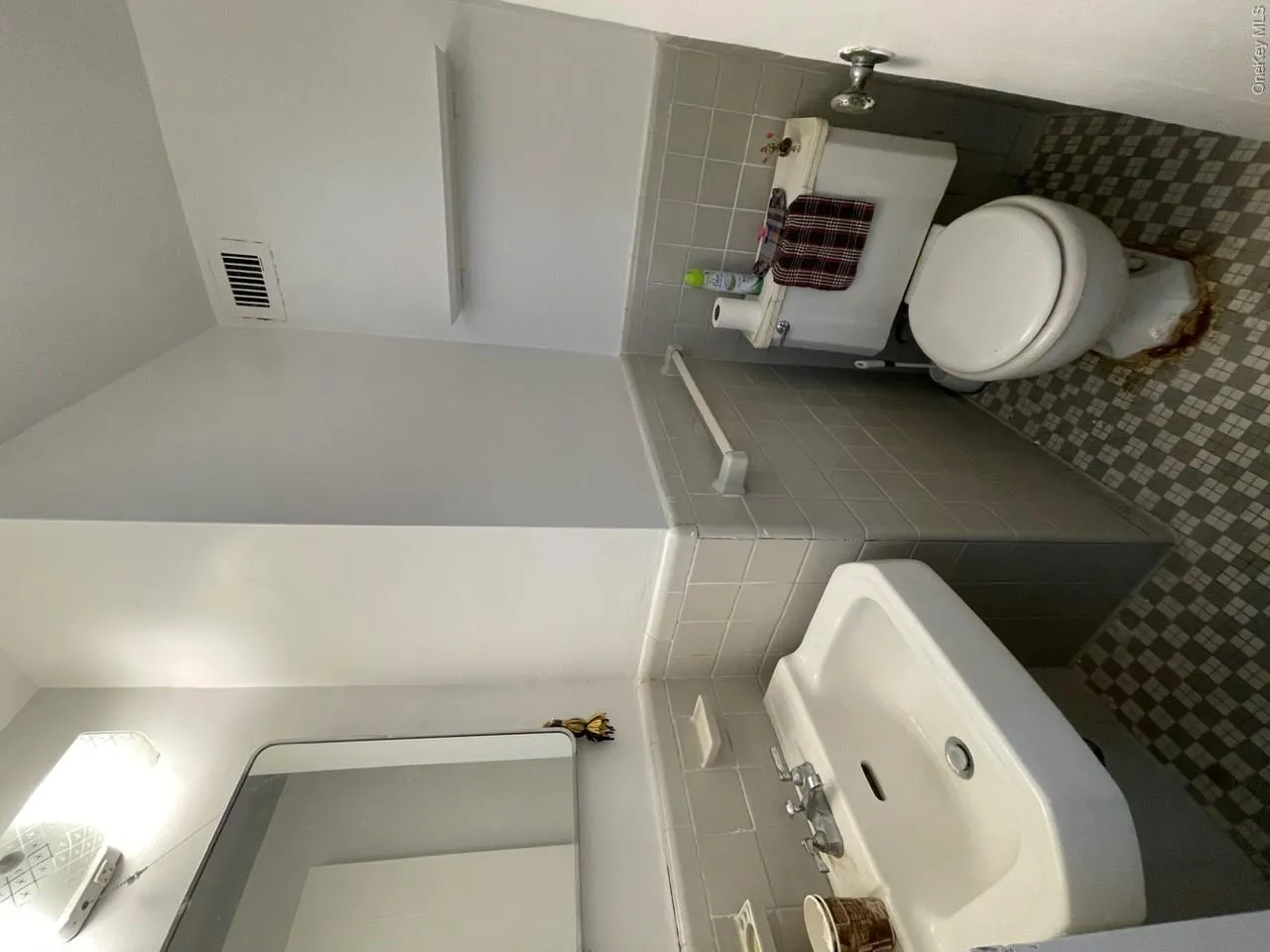 Half bathroom with tile walls, toilet, a wainscoted wall, a sink, and visible vents Half bathroom with tile walls, toilet, a wainscoted wall, a sink, and visible vents