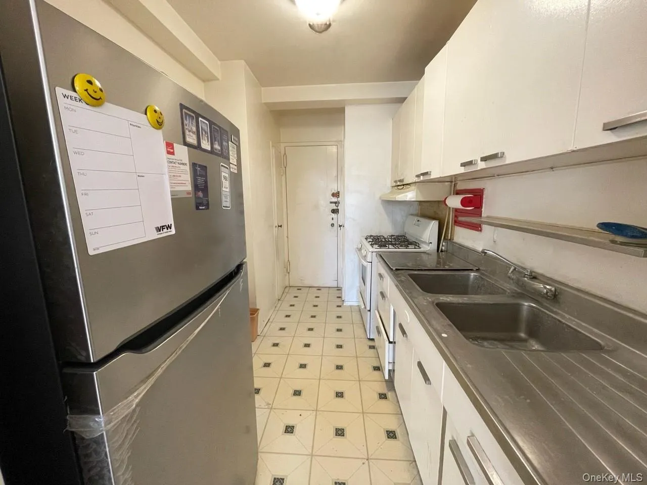Kitchen with under cabinet range hood, freestanding refrigerator, white cabinets, white range with gas stovetop, and light floors Kitchen with under cabinet range hood, freestanding refrigerator, white cabinets, white range with gas stovetop, and light floors