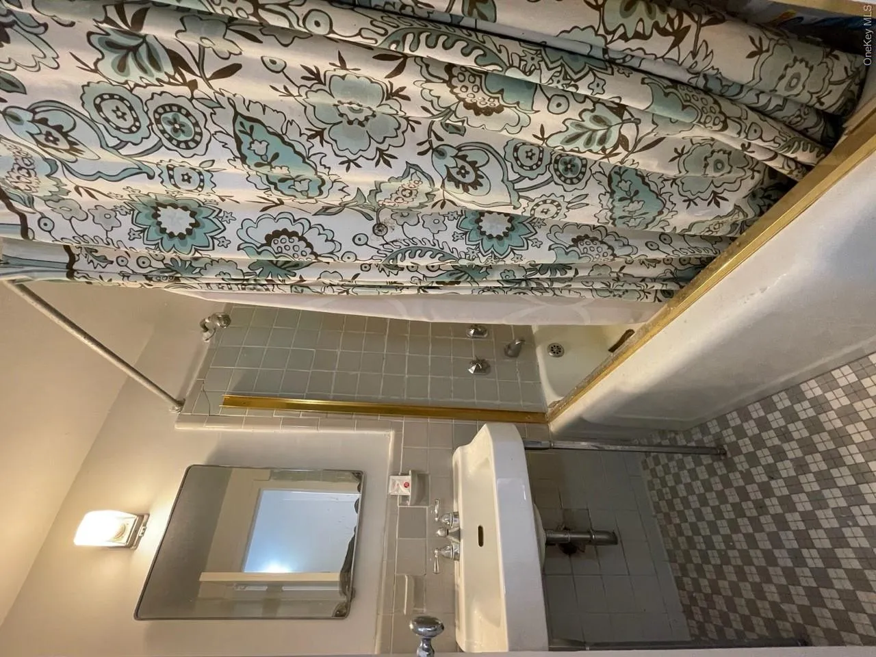 Full bathroom featuring a sink, shower / bath combination with curtain, tile walls, and tile patterned floors Full bathroom featuring a sink, shower / bath combination with curtain, tile walls, and tile patterned floors