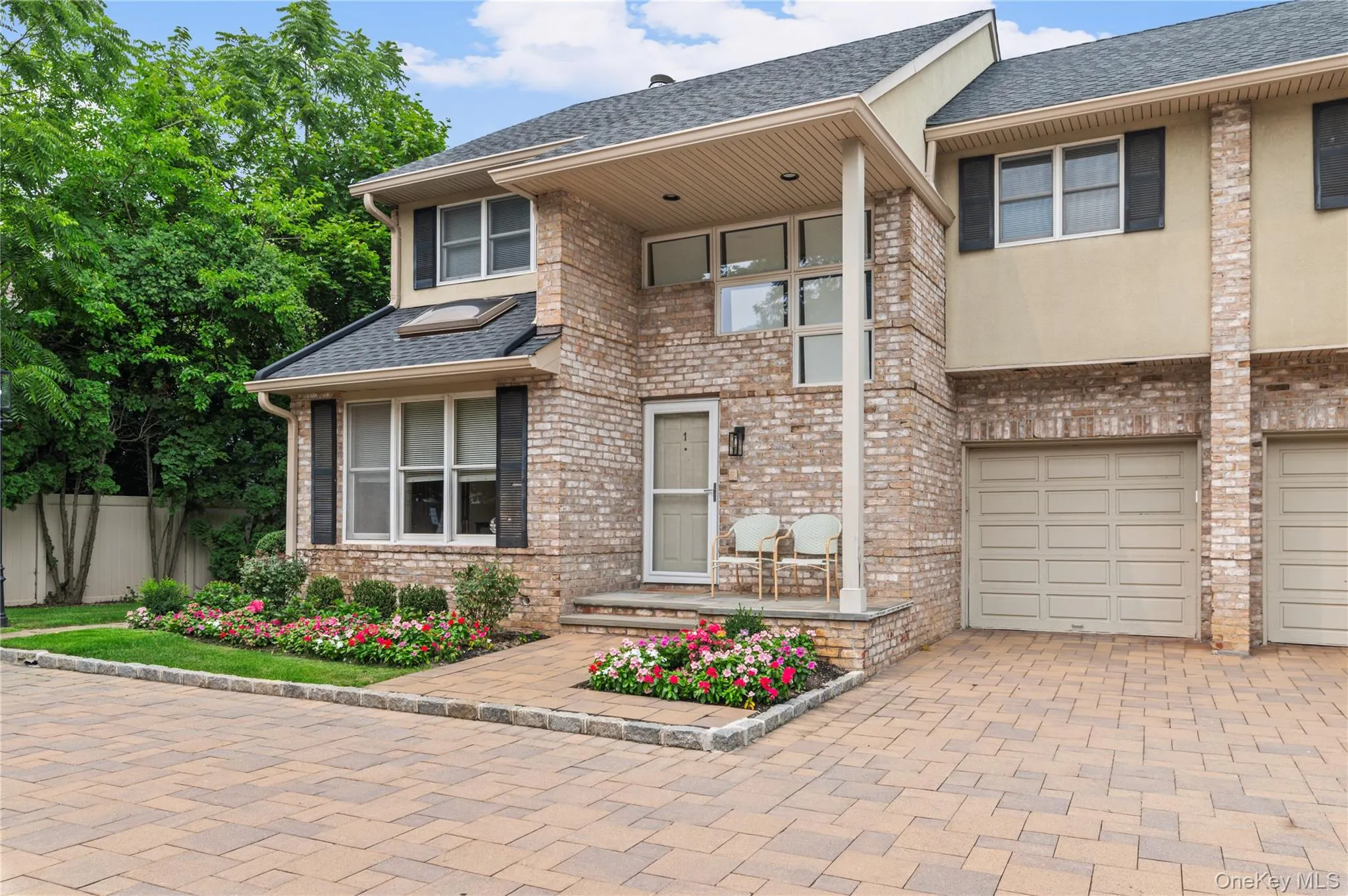 Brick facade residence featuring a covered entry, integrated garage, and a paver driveway Brick facade residence featuring a covered entry, integrated garage, and a paver driveway