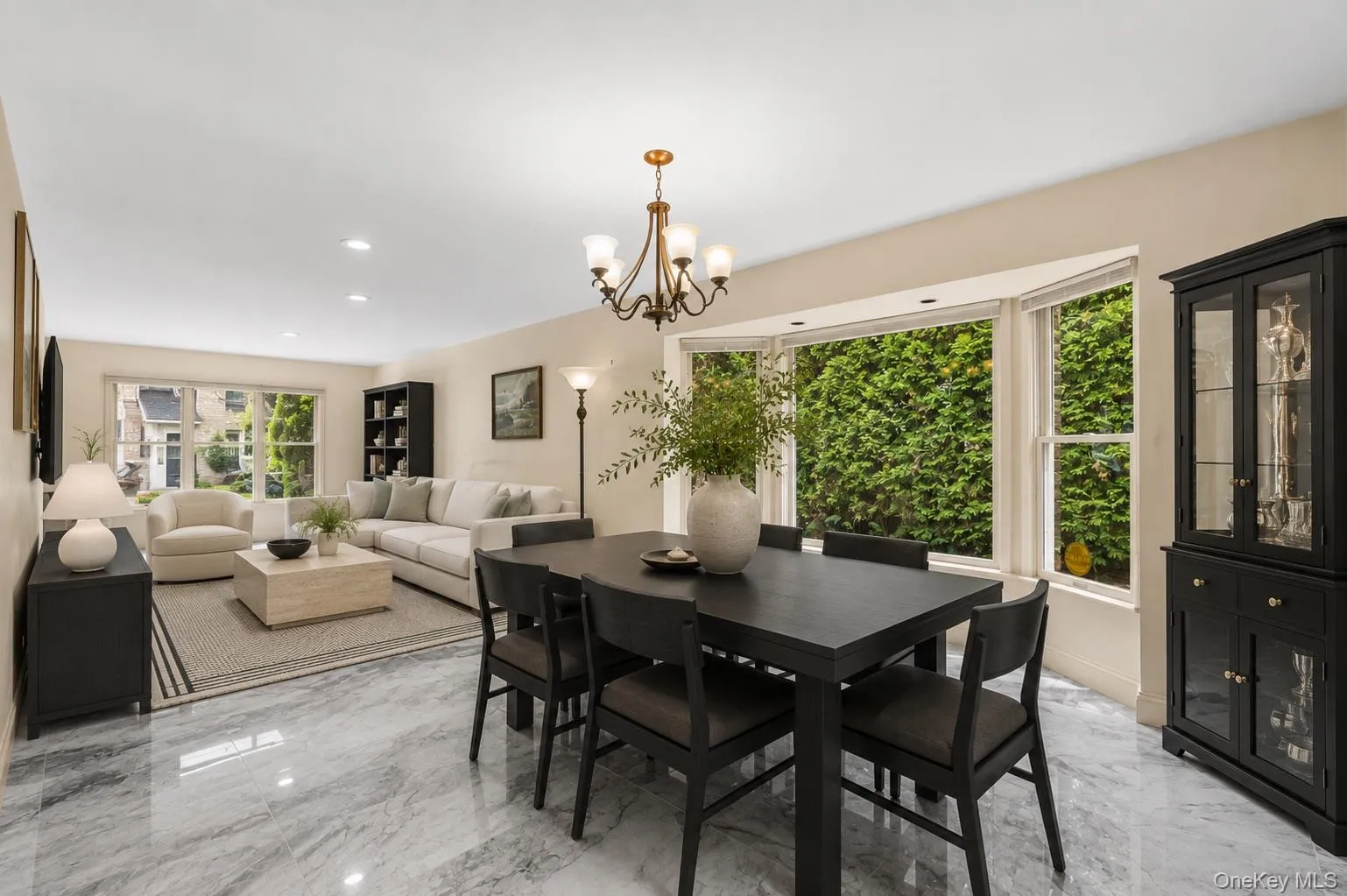Open-concept living and dining area featuring polished marble-finish flooring and a bay window Open-concept living and dining area featuring polished marble-finish flooring and a bay window