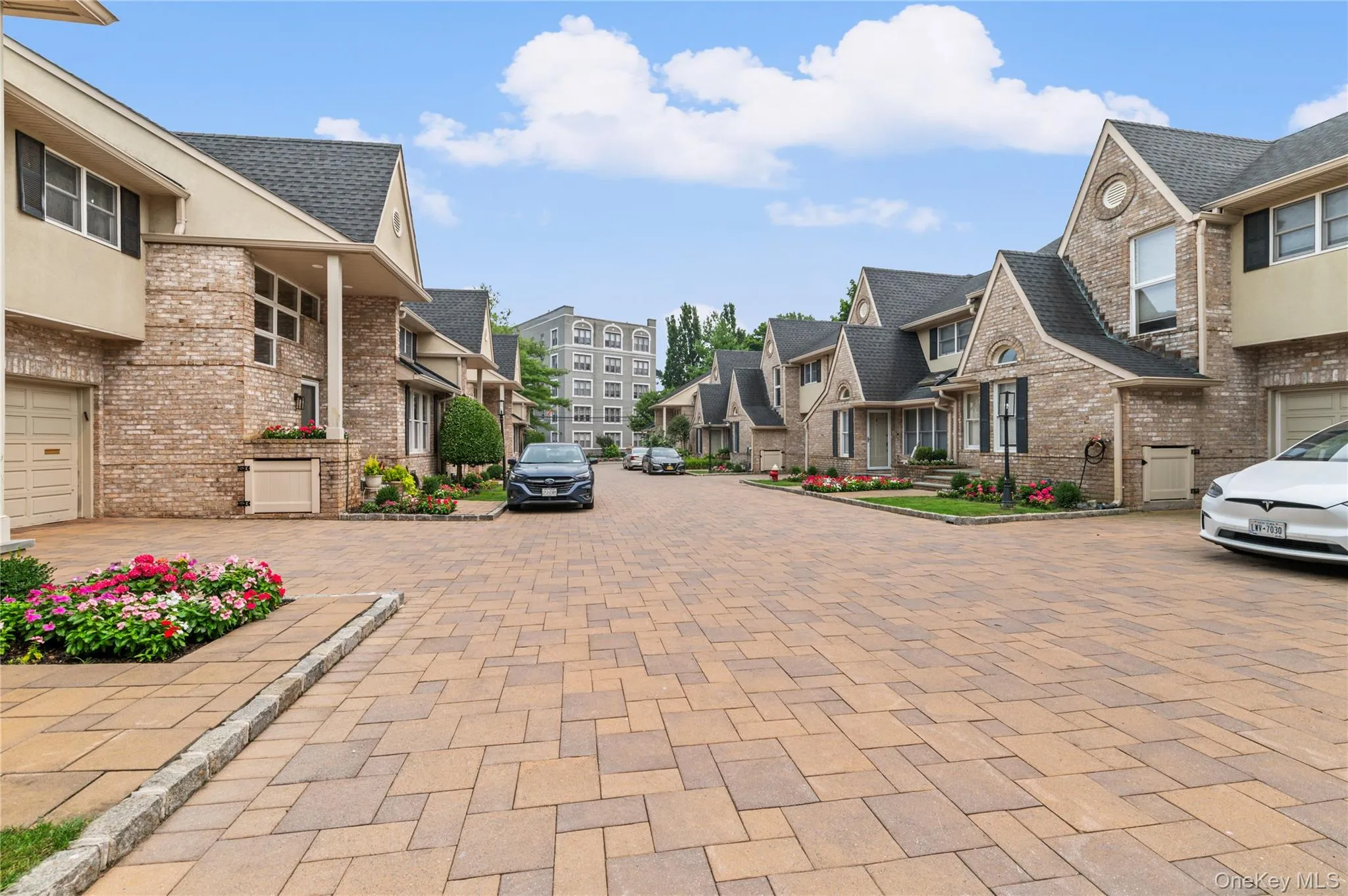 Paver driveway leading to a community of brick-exterior townhomes Paver driveway leading to a community of brick-exterior townhomes