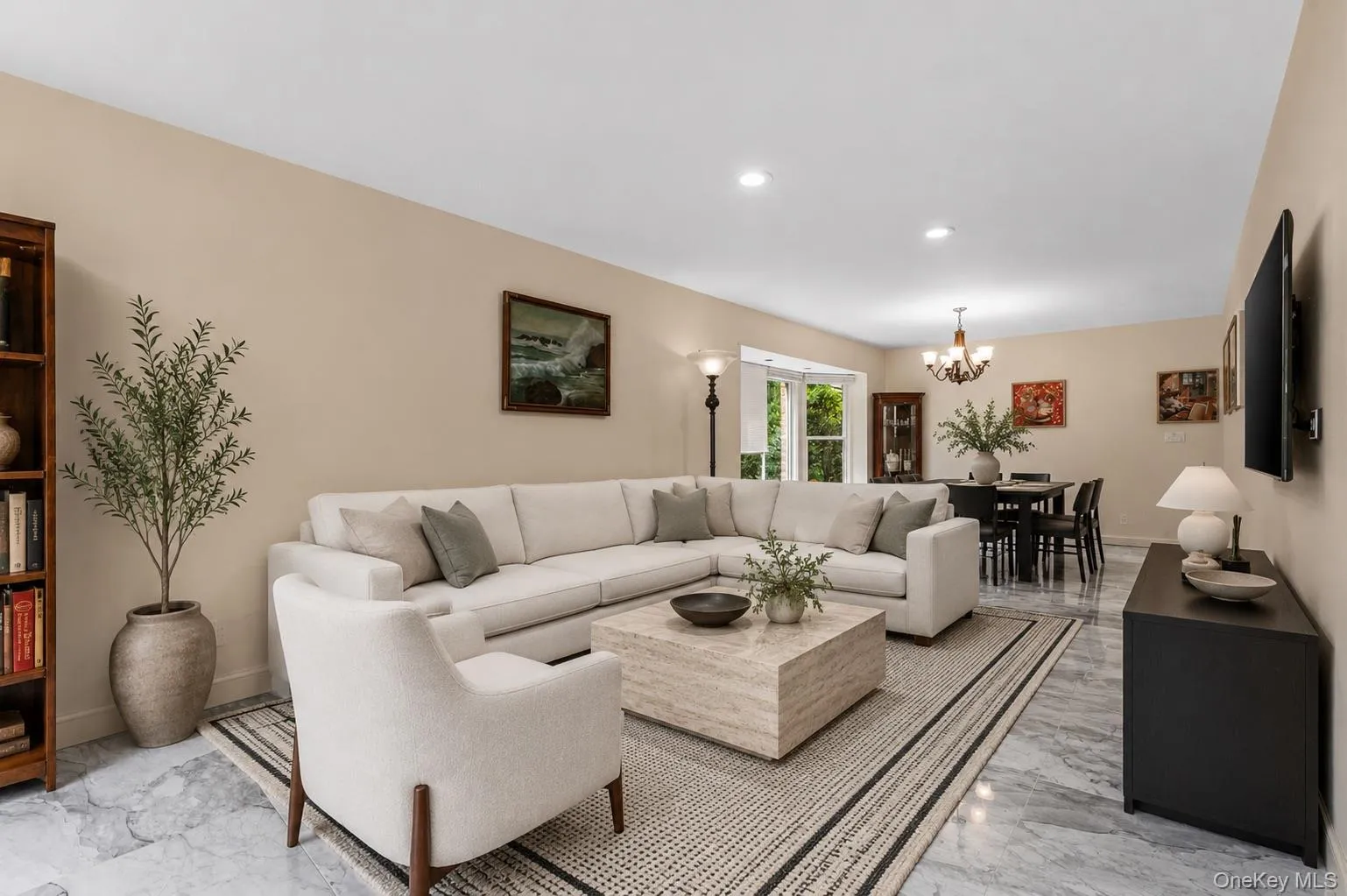 Open-concept living area with light-toned walls and polished stone flooring Open-concept living area with light-toned walls and polished stone flooring
