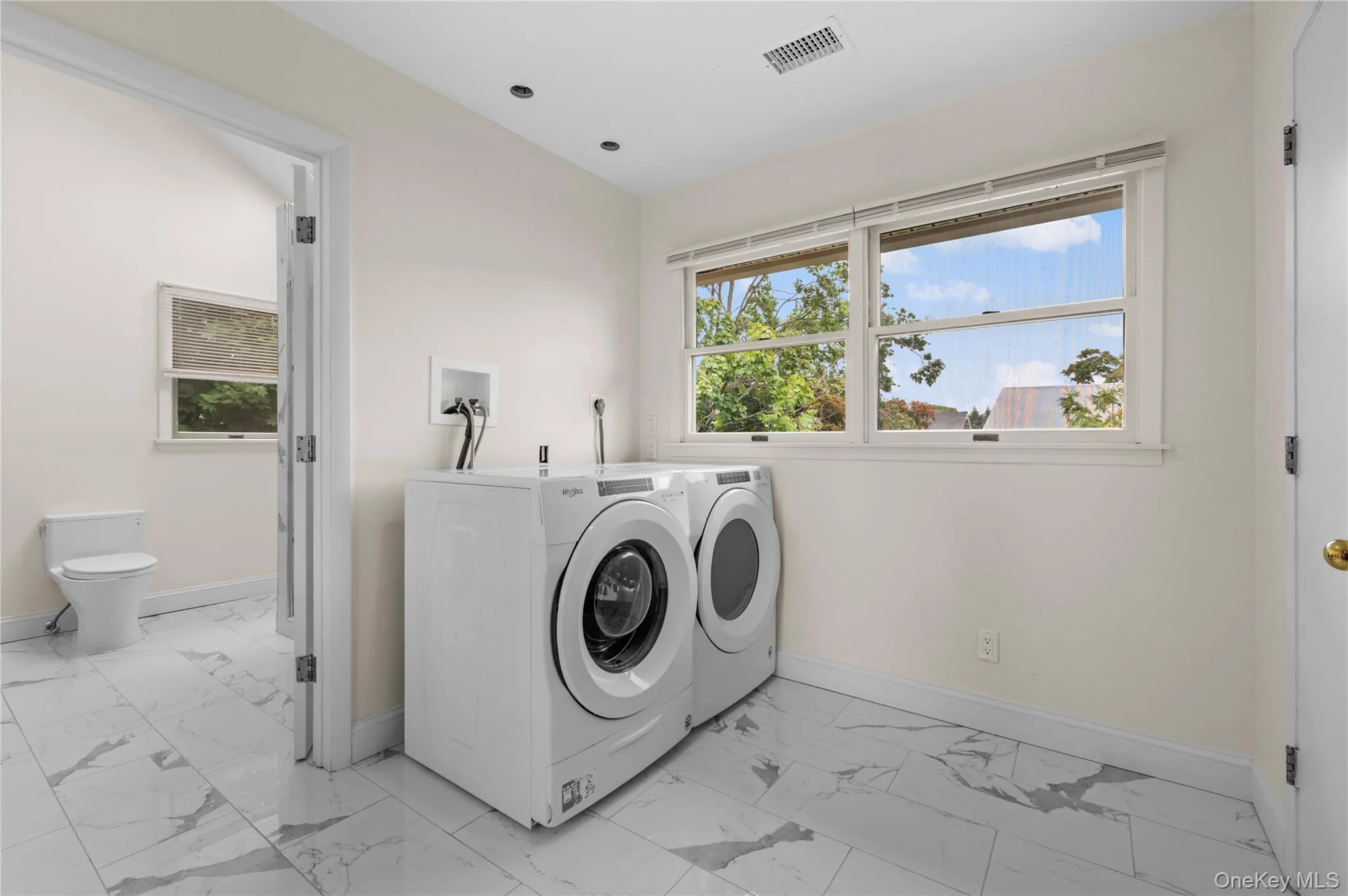 Dedicated laundry area featuring a front-load washer and dryer, tile flooring, and recessed ceiling lighting Dedicated laundry area featuring a front-load washer and dryer, tile flooring, and recessed ceiling lighting
