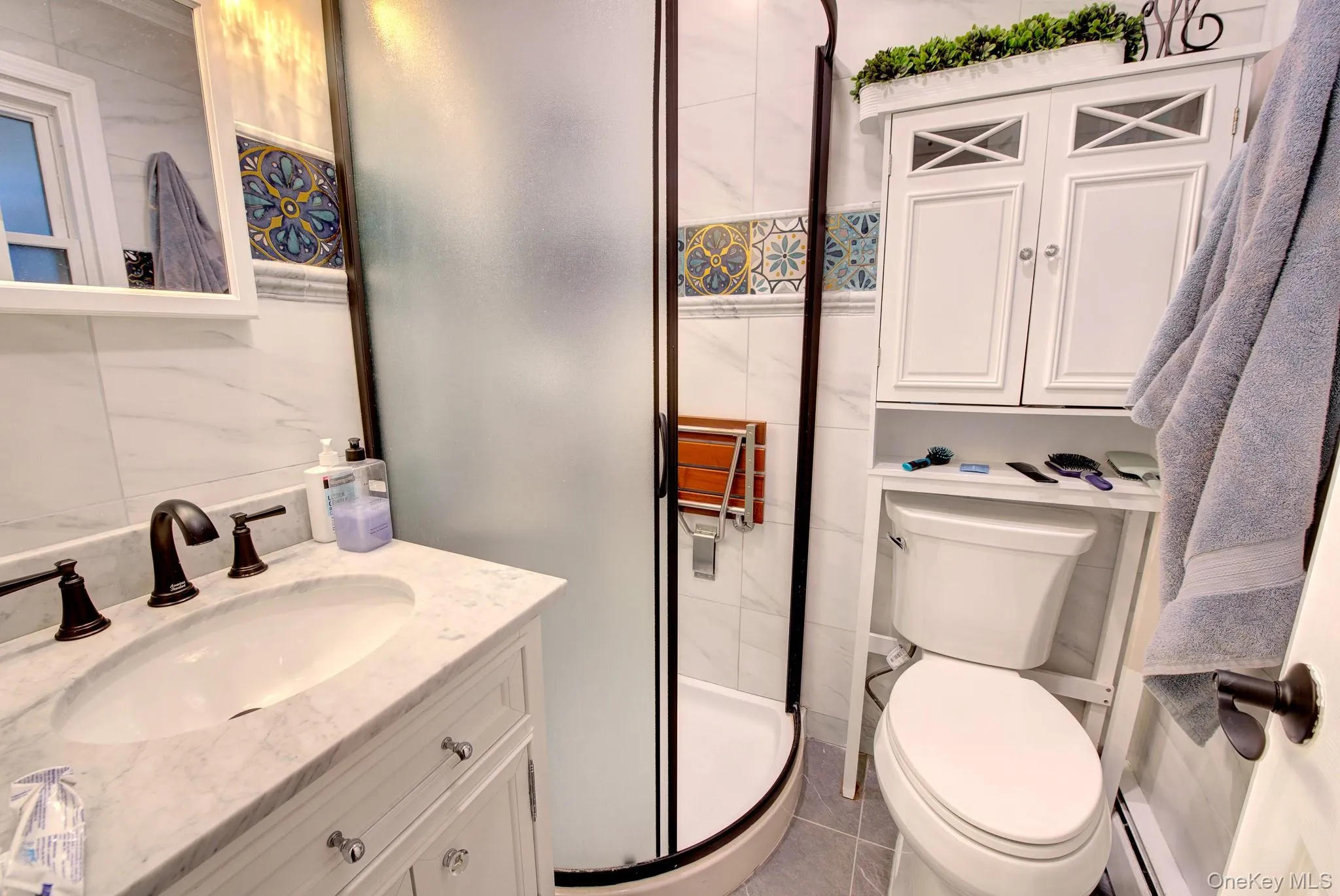 Bathroom featuring a white vanity with an undermount sink, dark bronze faucet, and a frosted glass shower enclosure Bathroom featuring a white vanity with an undermount sink, dark bronze faucet, and a frosted glass shower enclosure