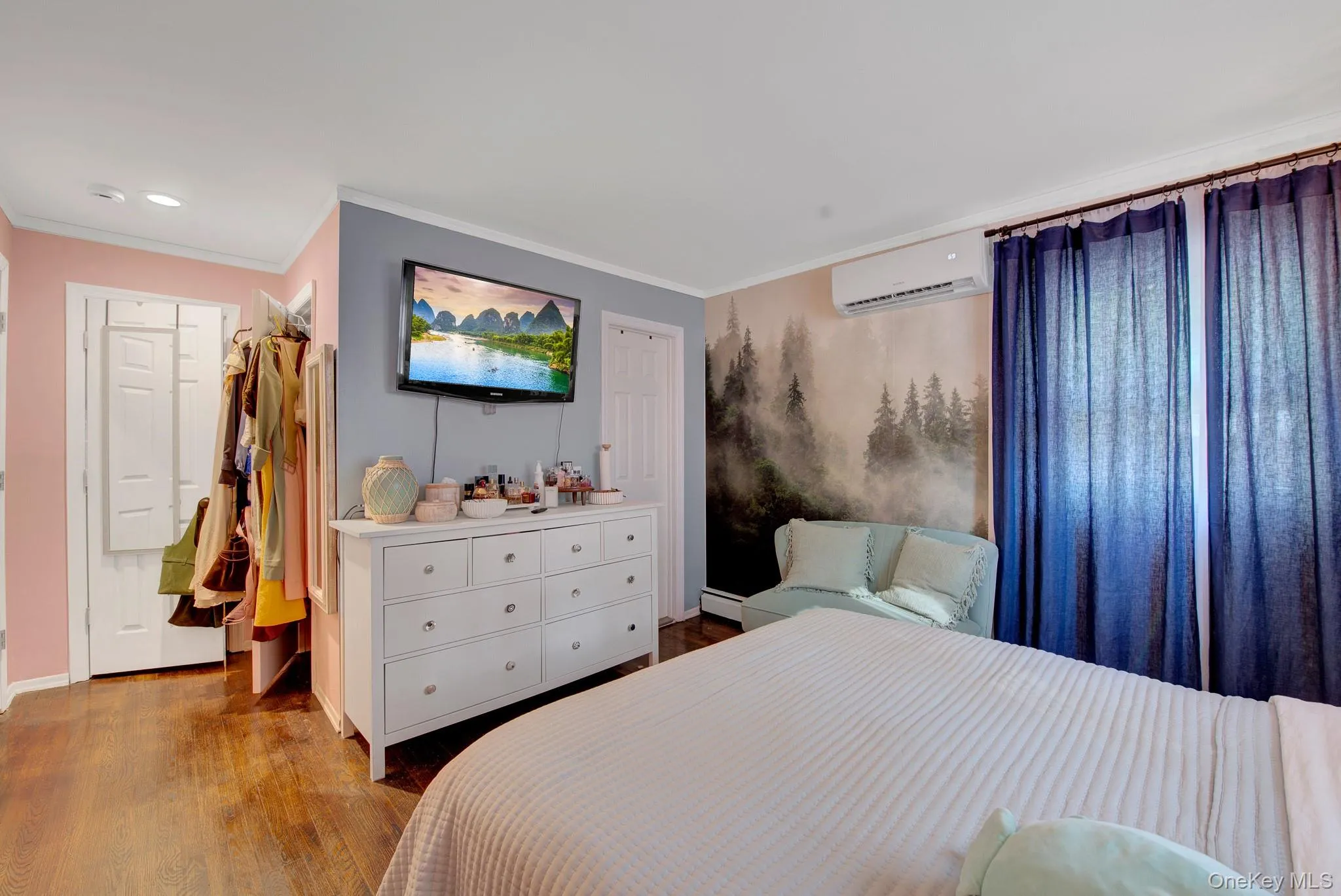 Bedroom featuring wood-finish flooring, a wall-mounted air conditioning unit, and a decorative wall mural Bedroom featuring wood-finish flooring, a wall-mounted air conditioning unit, and a decorative wall mural