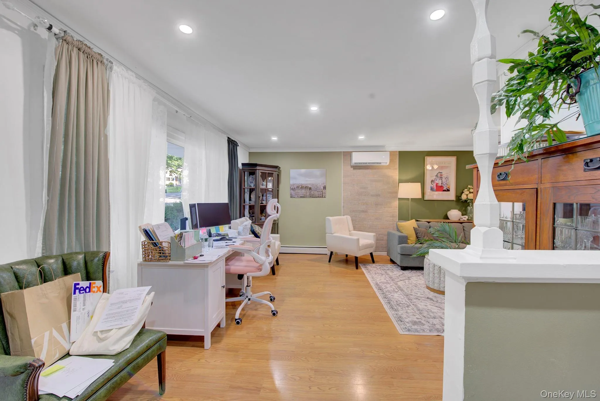 Open-concept living area with wood-finish flooring, recessed lighting, and a prominent decorative column Open-concept living area with wood-finish flooring, recessed lighting, and a prominent decorative column